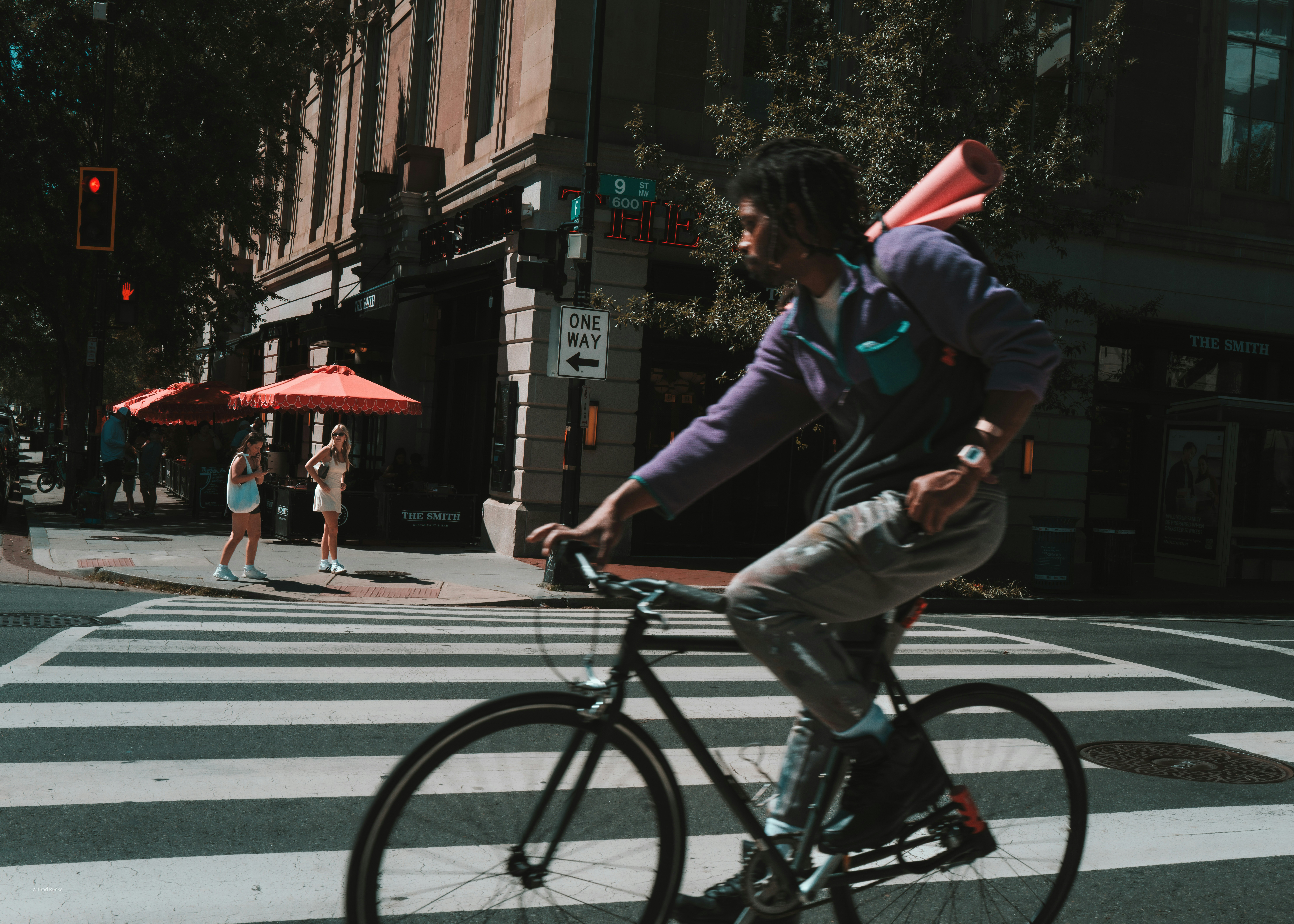 Man rides bicycle across a city crosswalk.