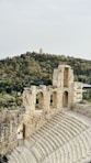 Ancient stone amphitheater ruins with a hilly landscape.