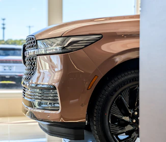 Close-up of a shiny brown car grille and wheel.