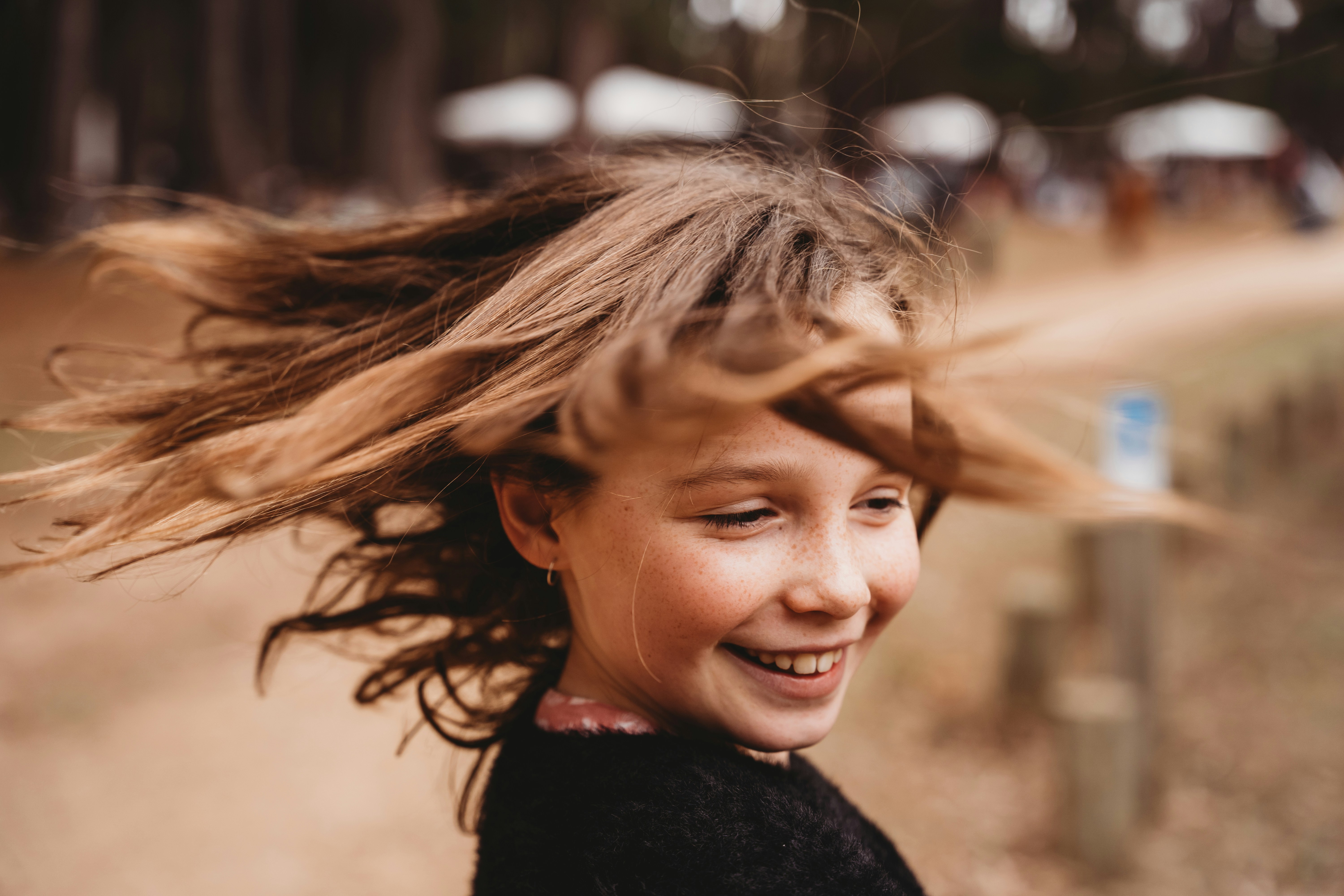Young girl with windblown hair laughing outdoors