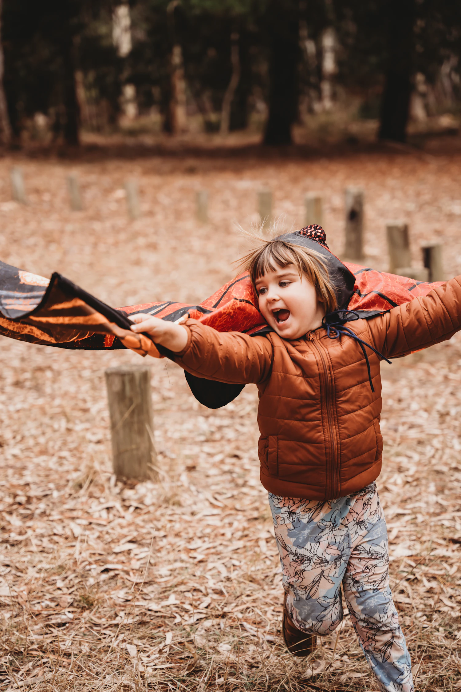 Young girl in a puffer coat running through an autumn forest with arms outstretched