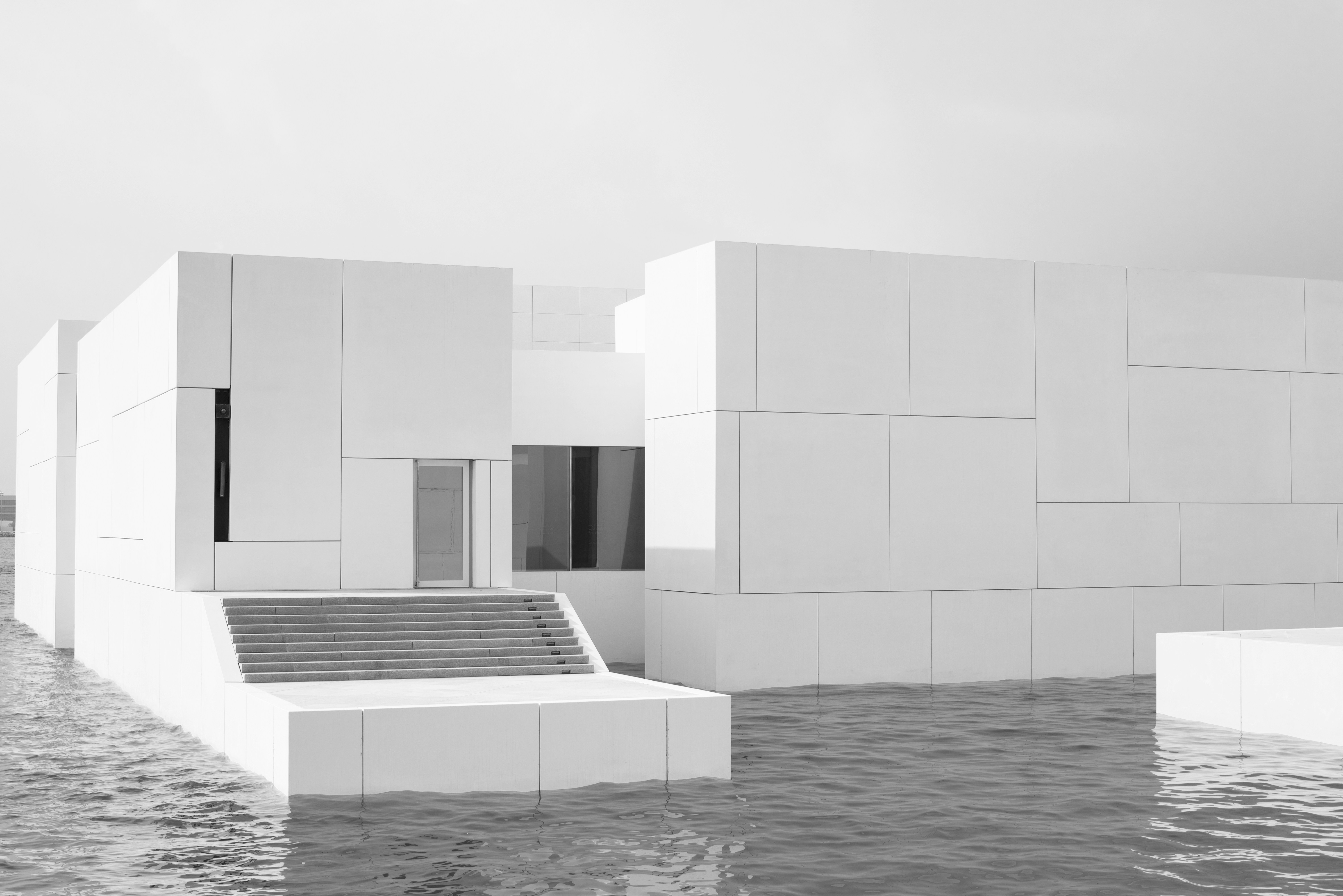 Modern white building partially submerged in water.