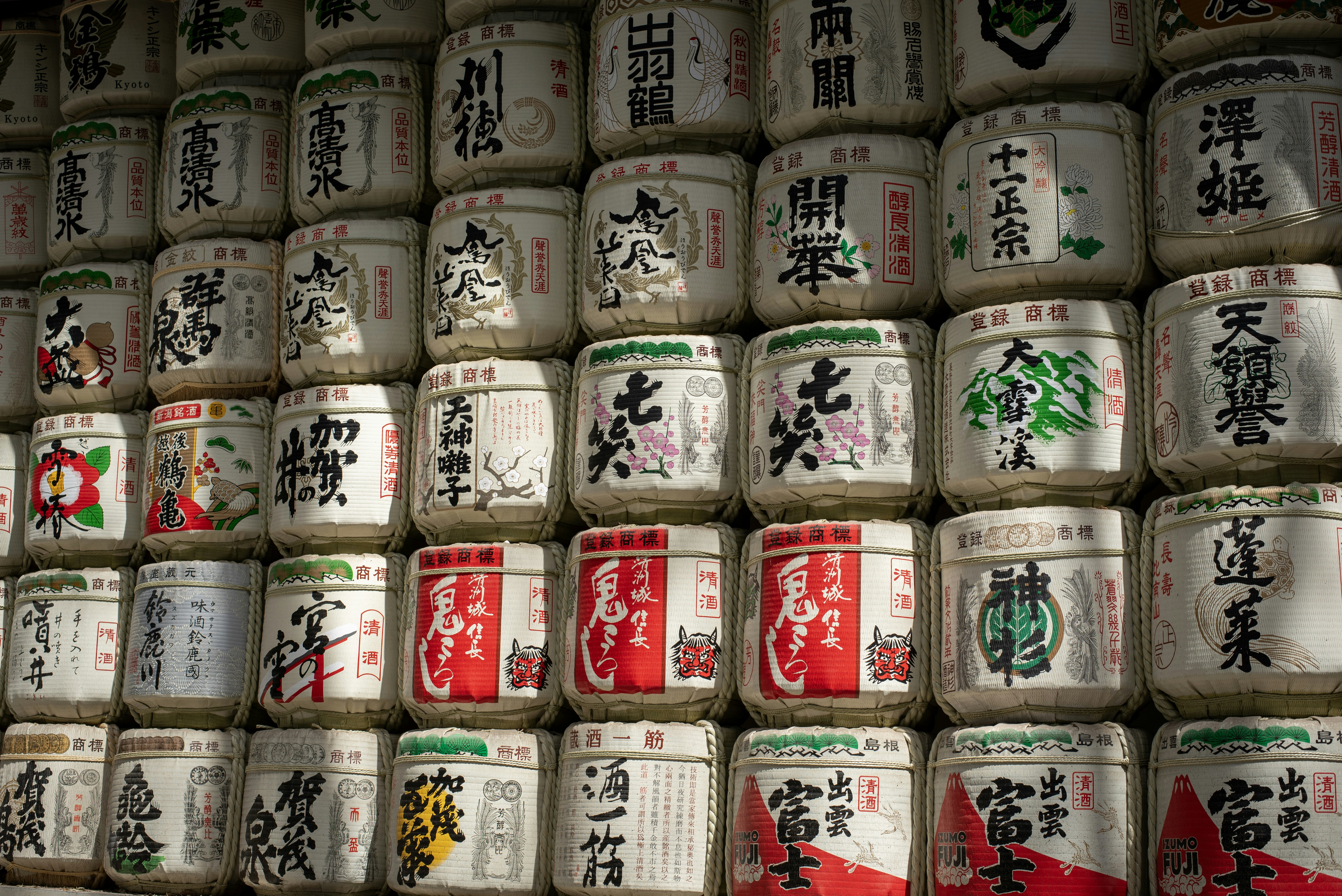 Wall of traditional japanese sake barrels with writing.