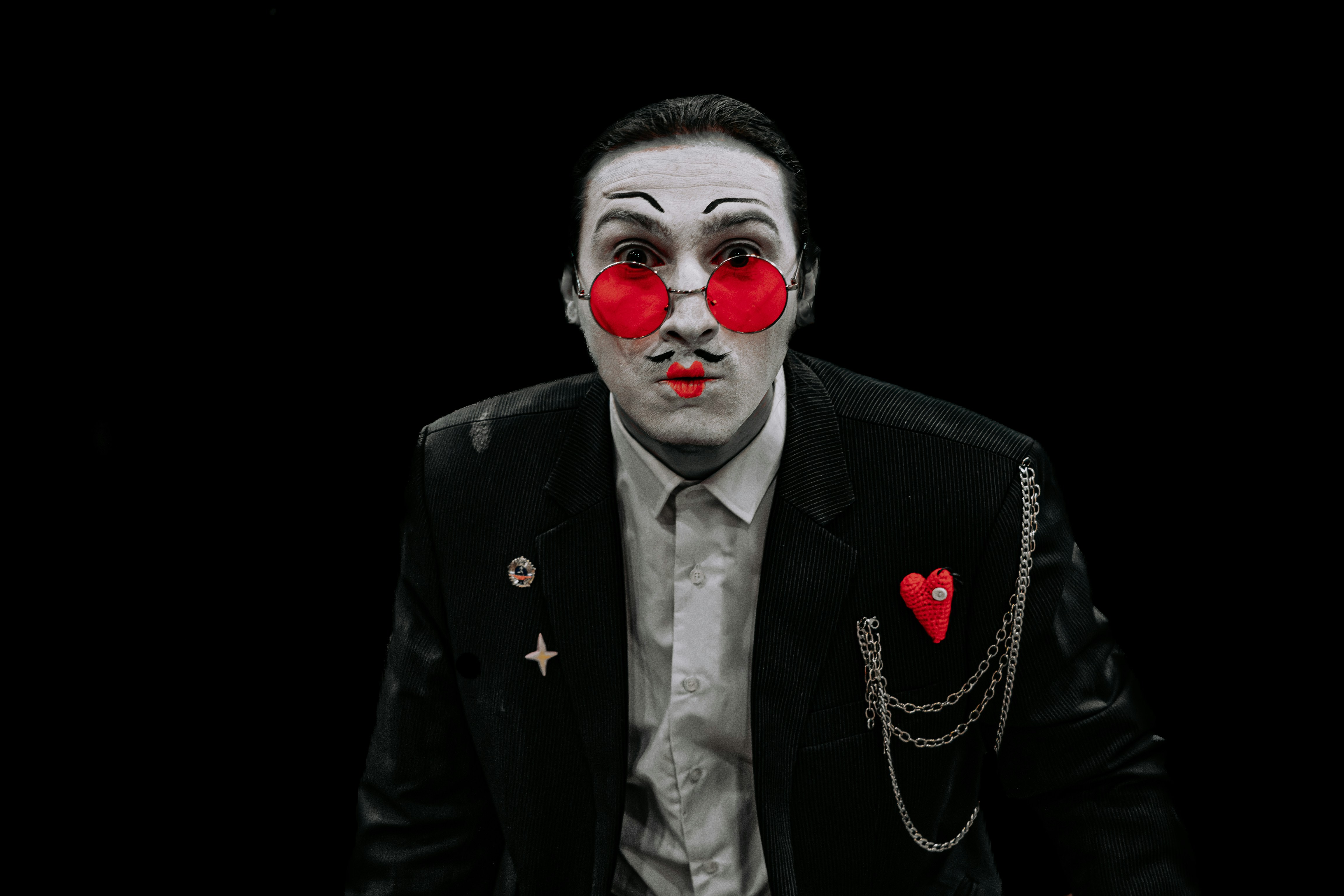 Man with theatrical makeup and red glasses