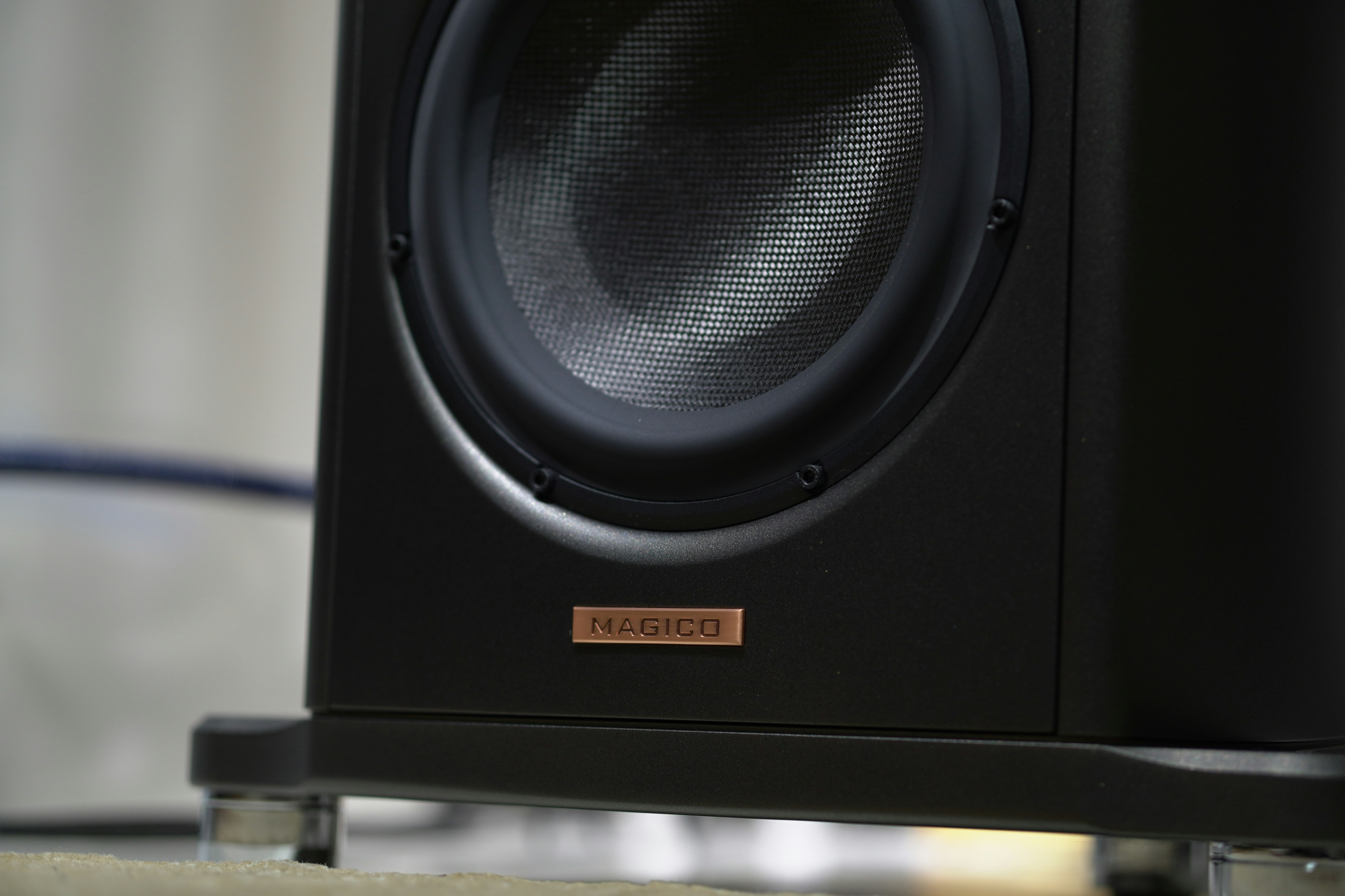 Close-up of a black speaker with a copper logo.