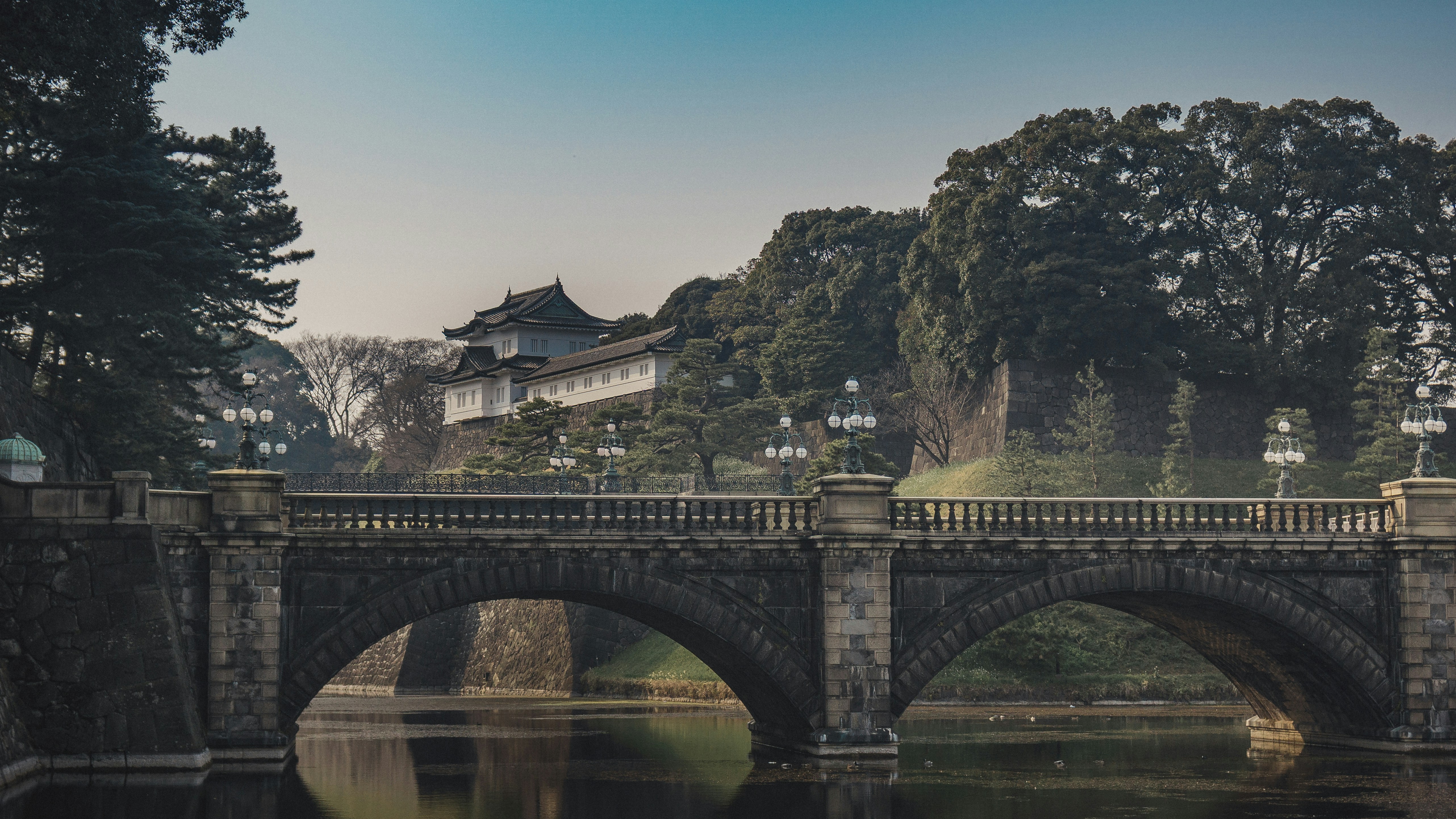 Stone bridge over water with traditional building.
