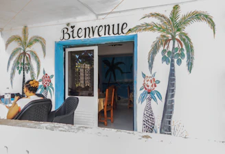 Entrance with "bienvenue" sign and palm tree paintings