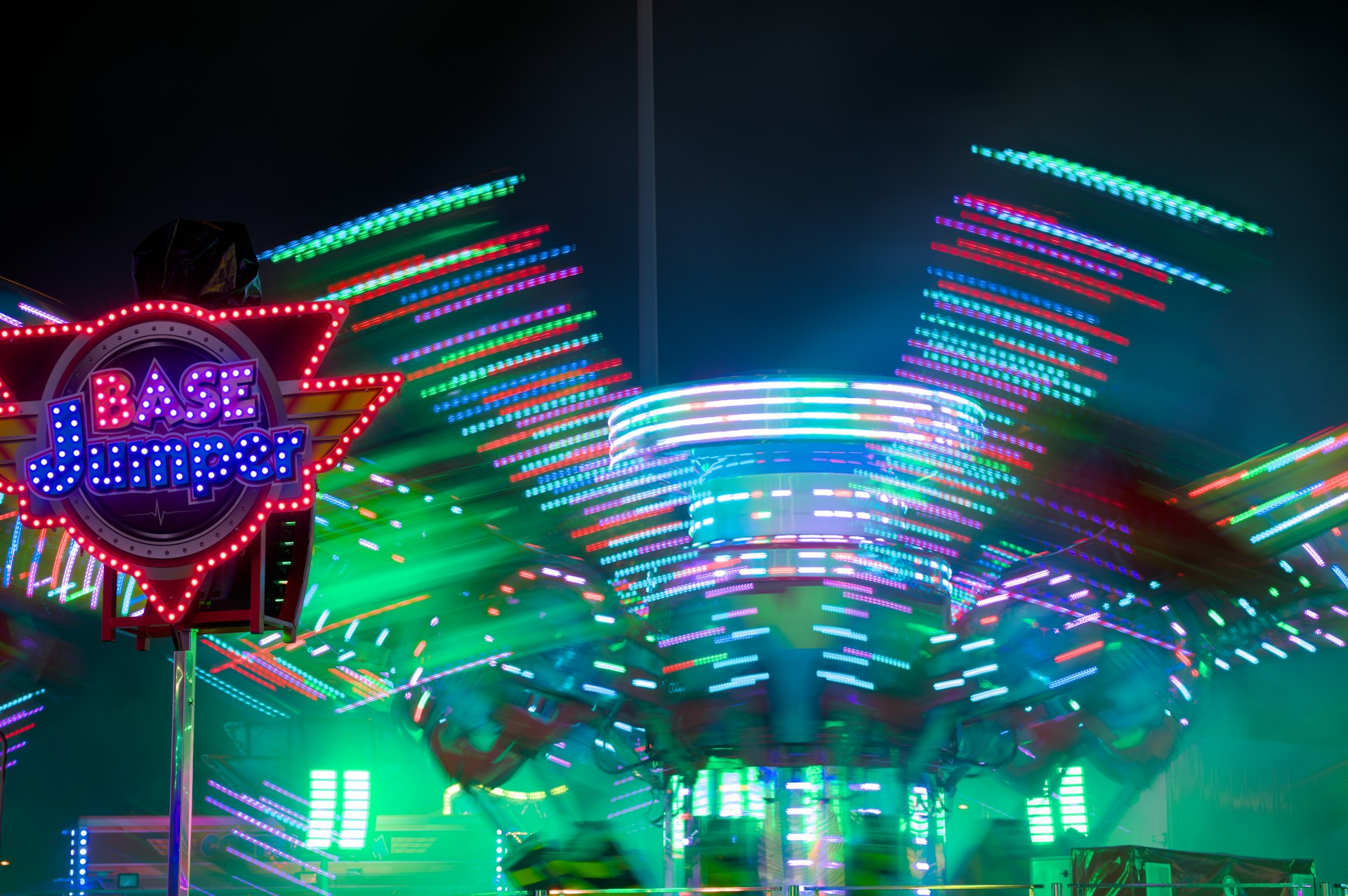 Spinning amusement park ride with colorful lights at night