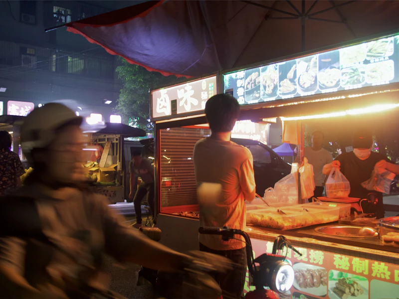 People at a brightly lit Asian night market food stall