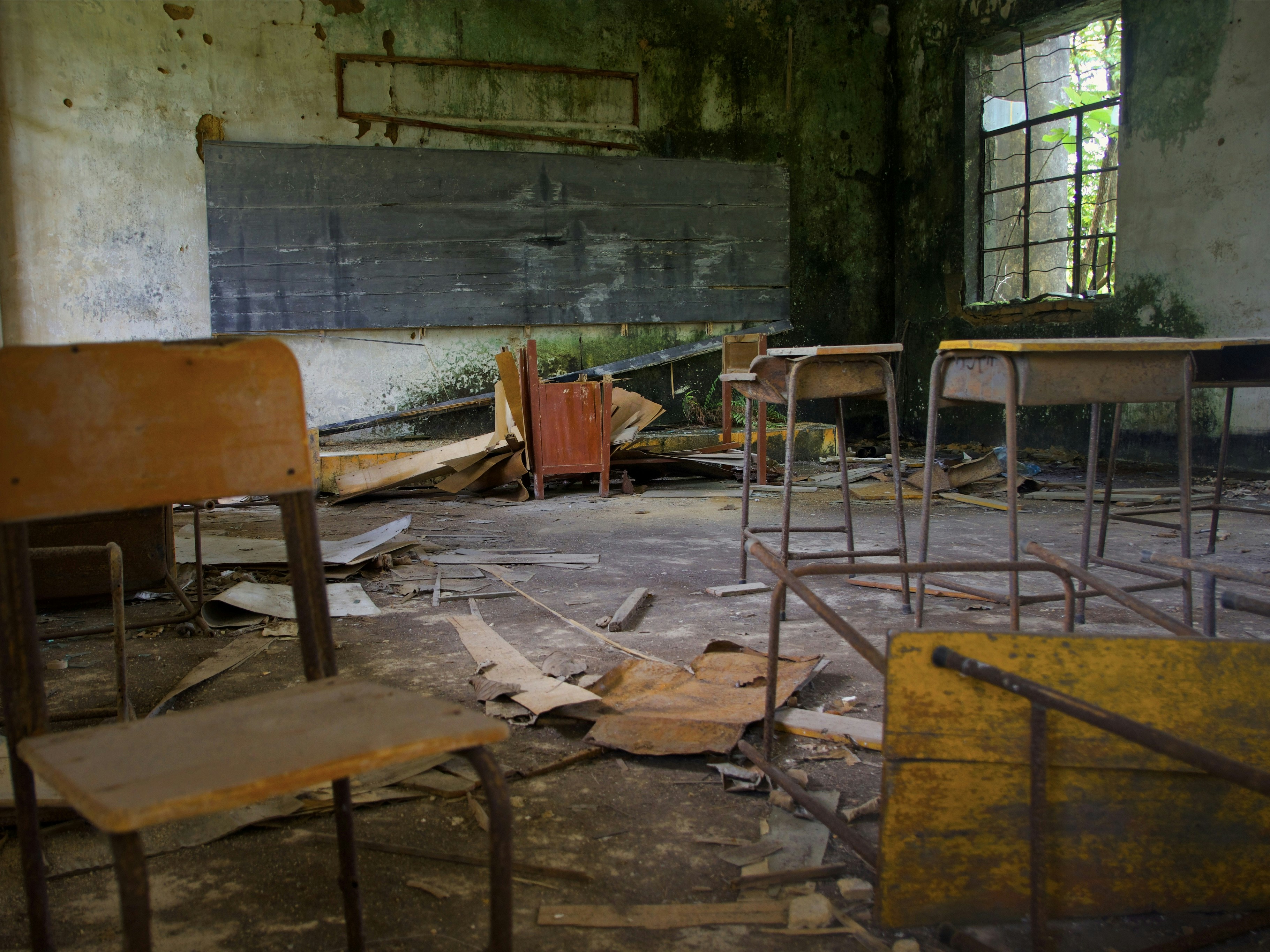 Abandoned classroom with desks and debris