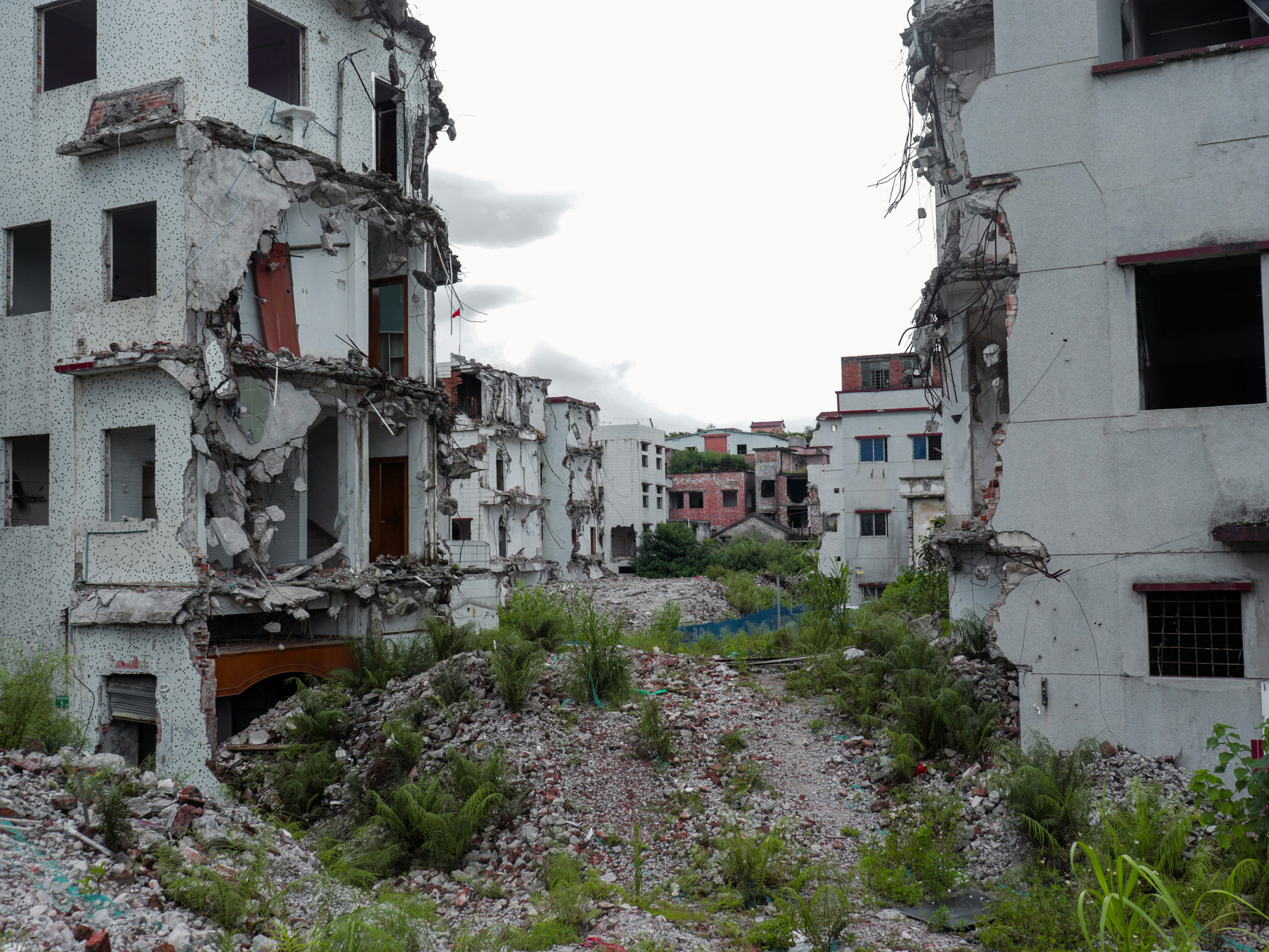 Edificios en ruinas cubiertos de vegetación bajo un cielo nublado