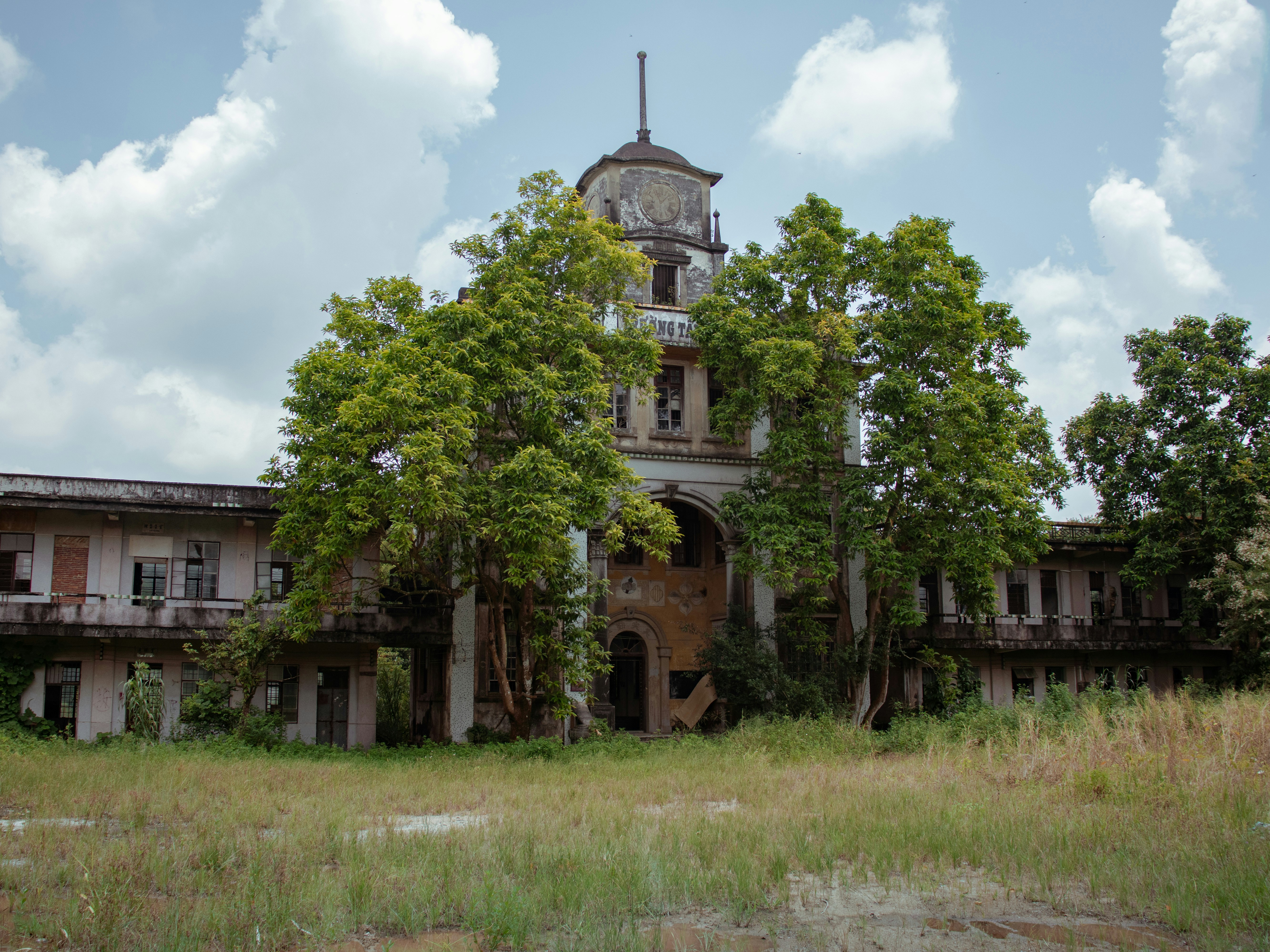 An old, overgrown abandoned building with a central tower.