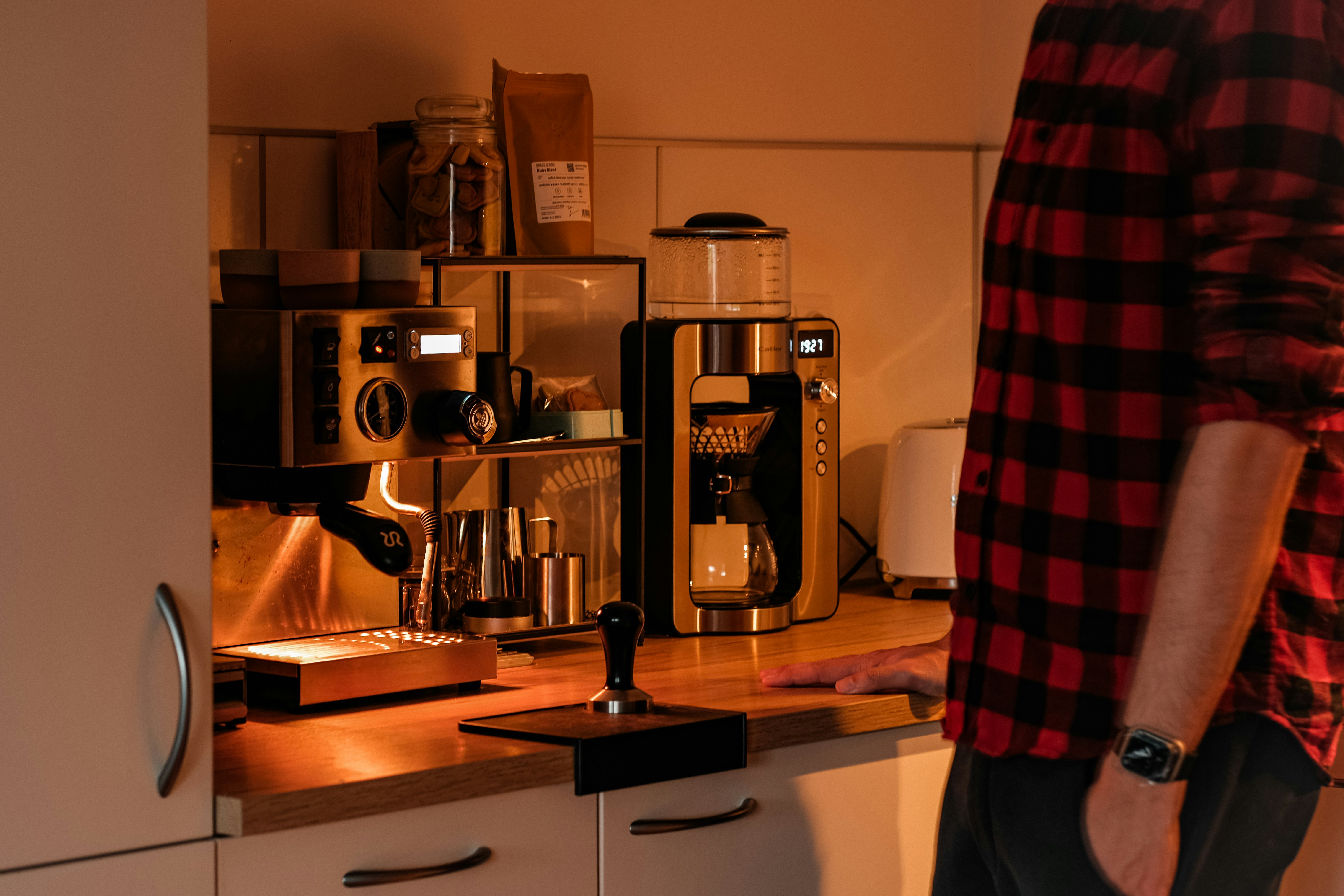 Person standing by coffee maker and grinder
