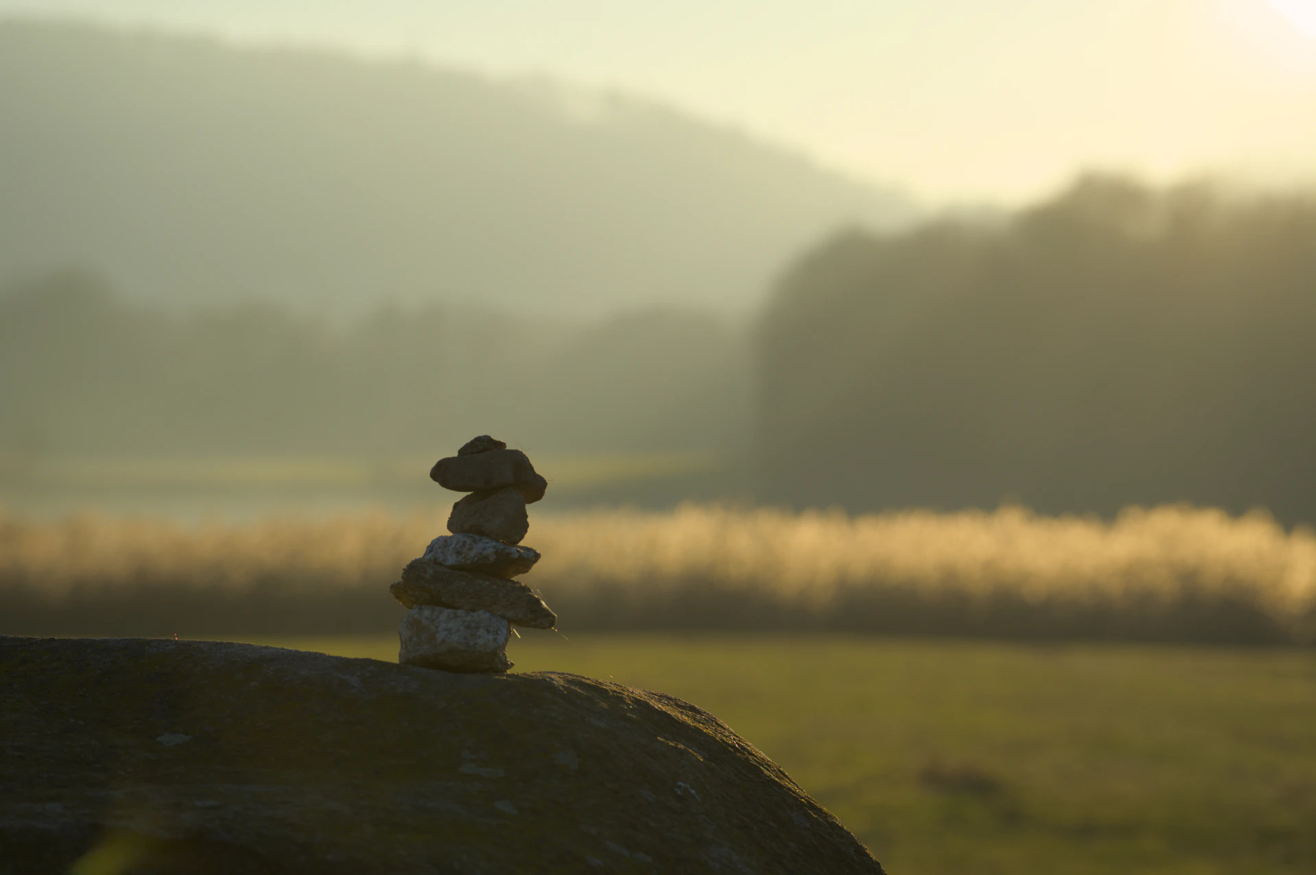 Stacked stones on a rock at sunrise