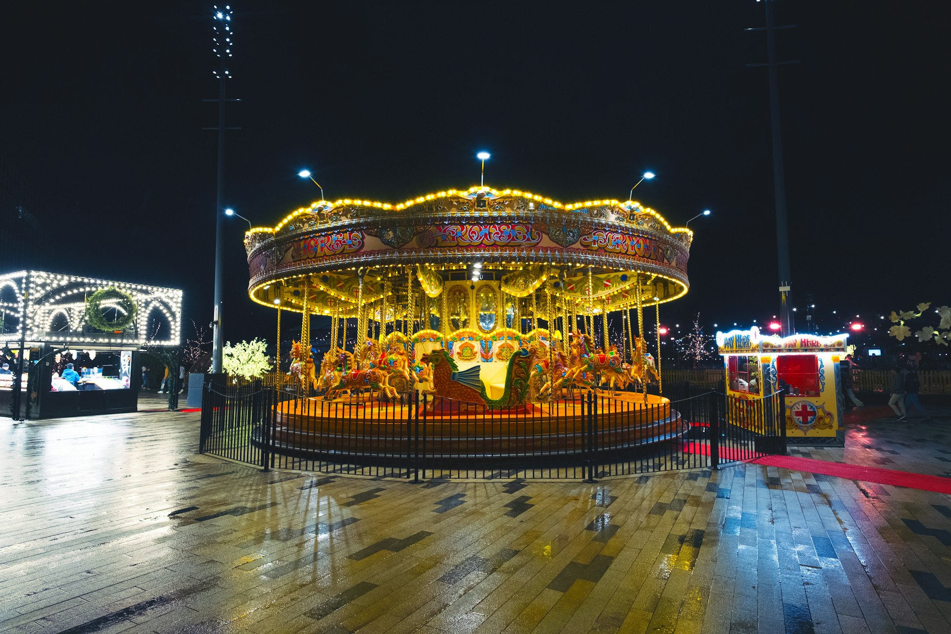 A brightly lit carousel at night with reflections