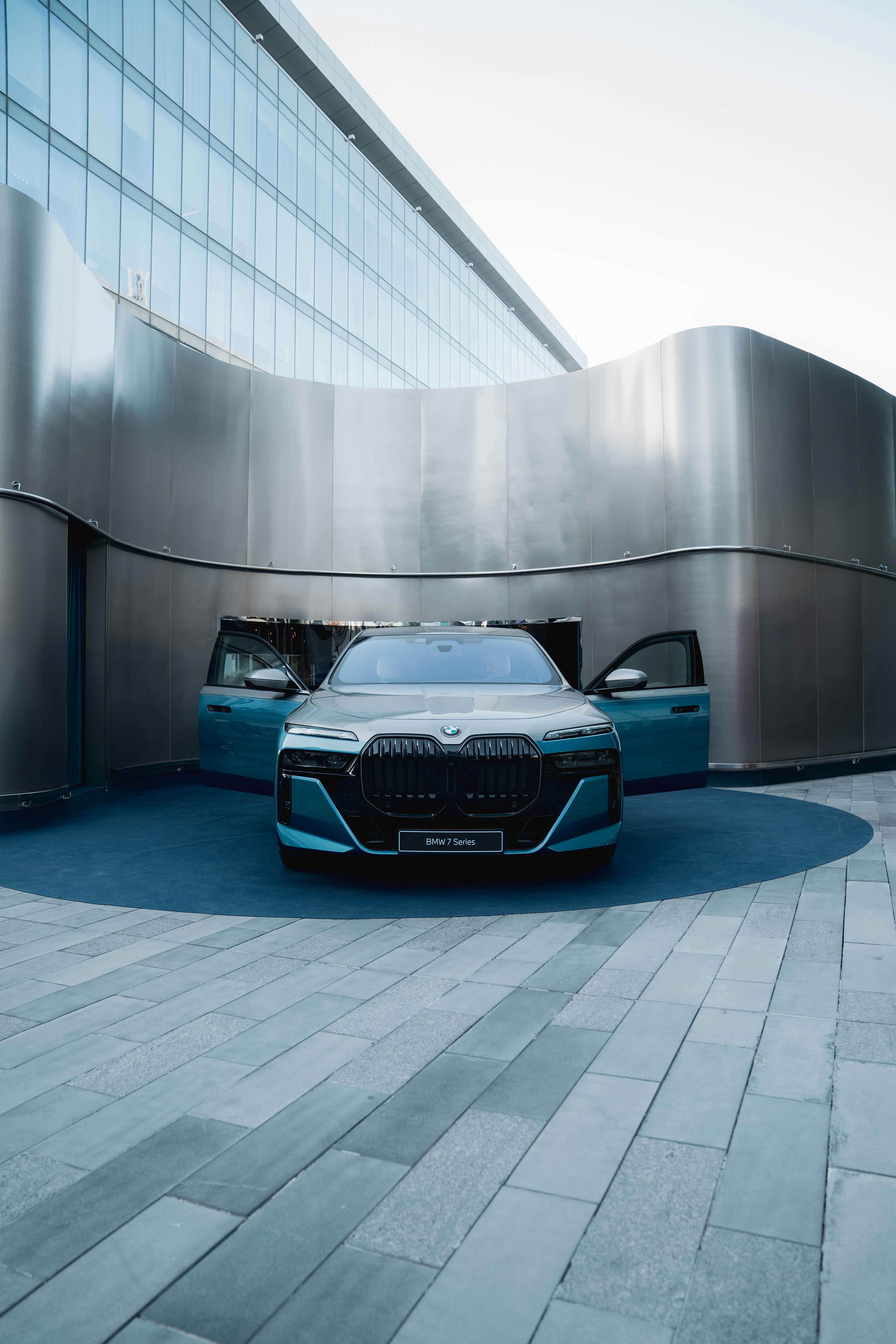 A teal BMW sedan parked outside a modern building.
