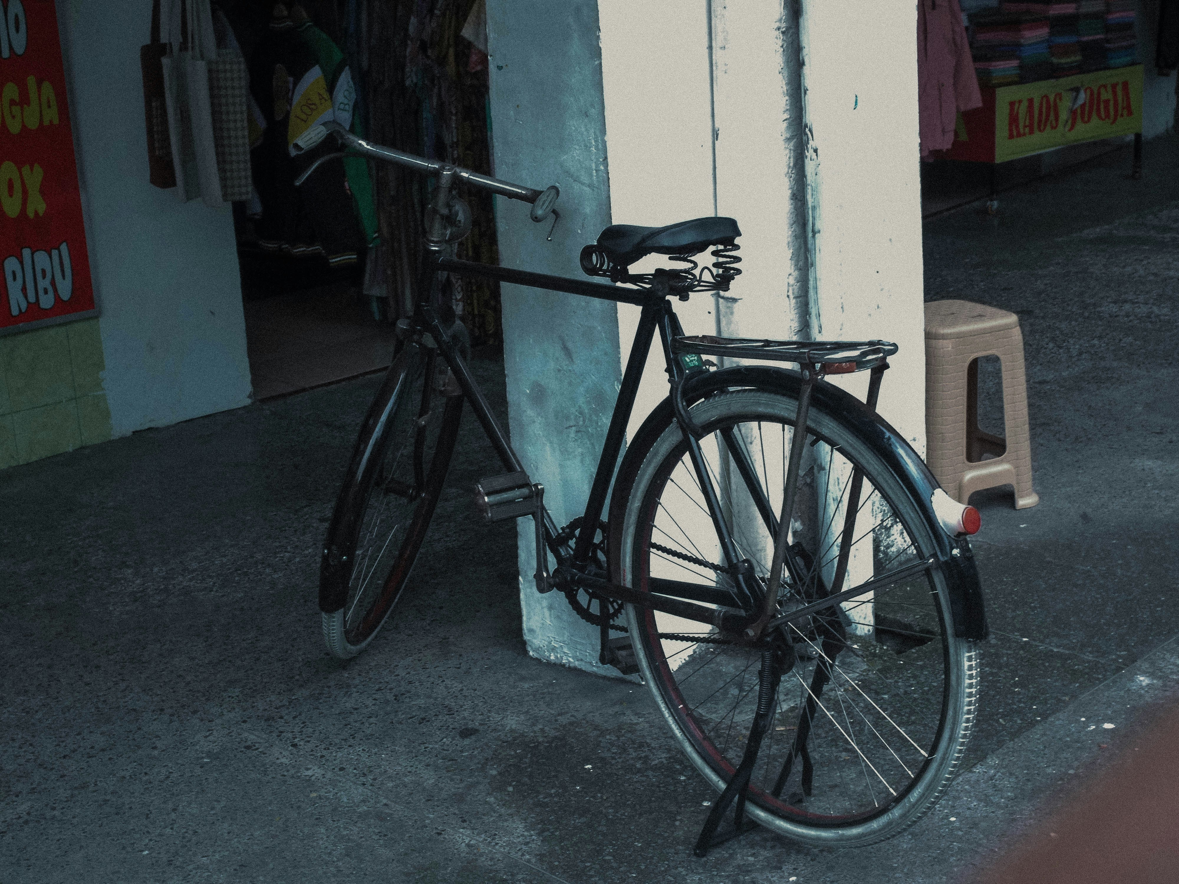 A vintage black bicycle leaning against a wall.
