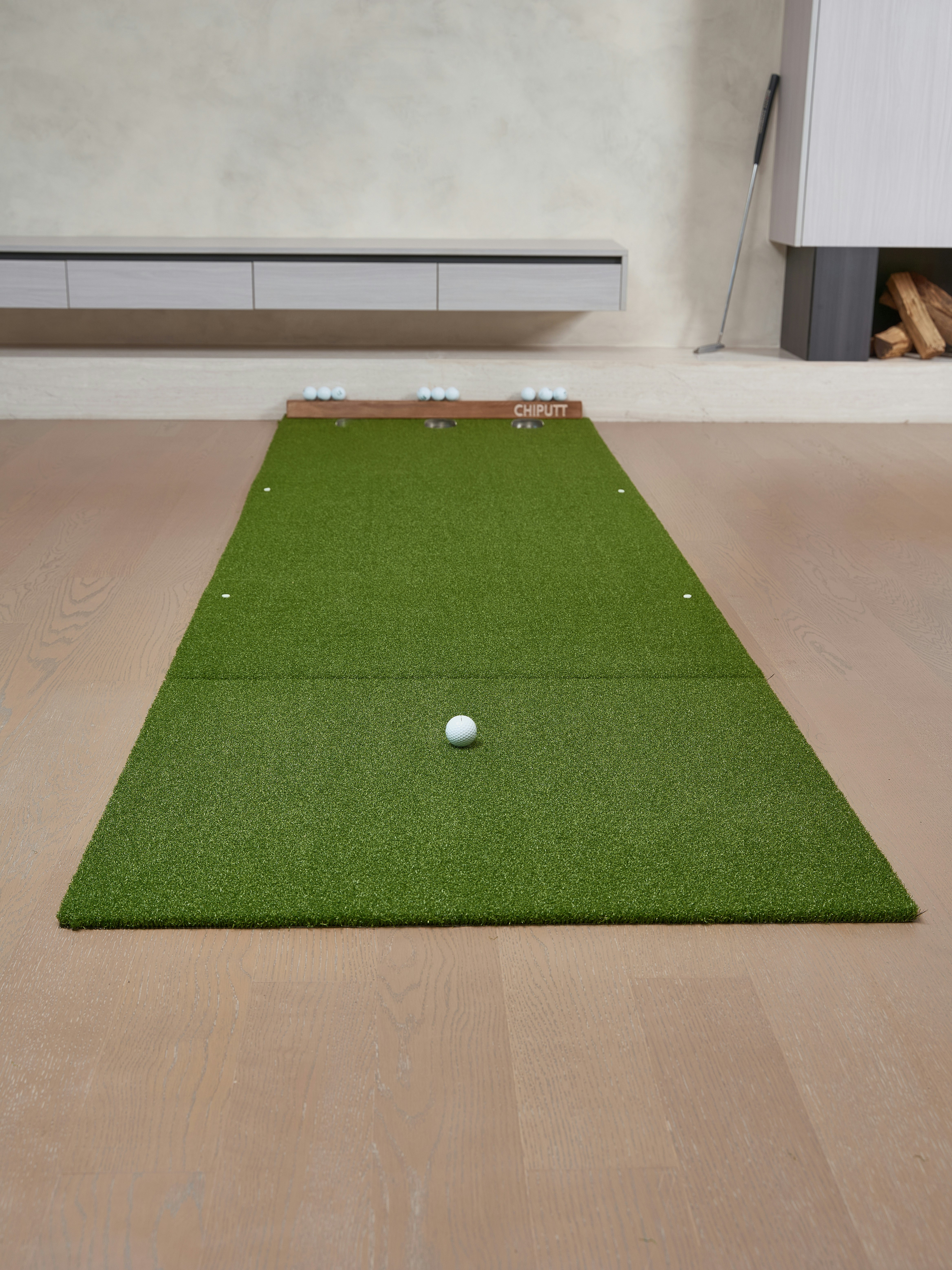 Golf putting green with balls and club indoors