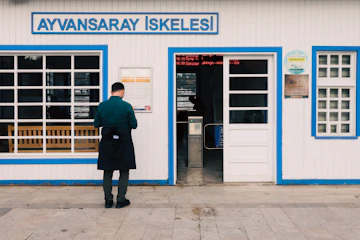 Man standing outside a ferry terminal building entrance.
