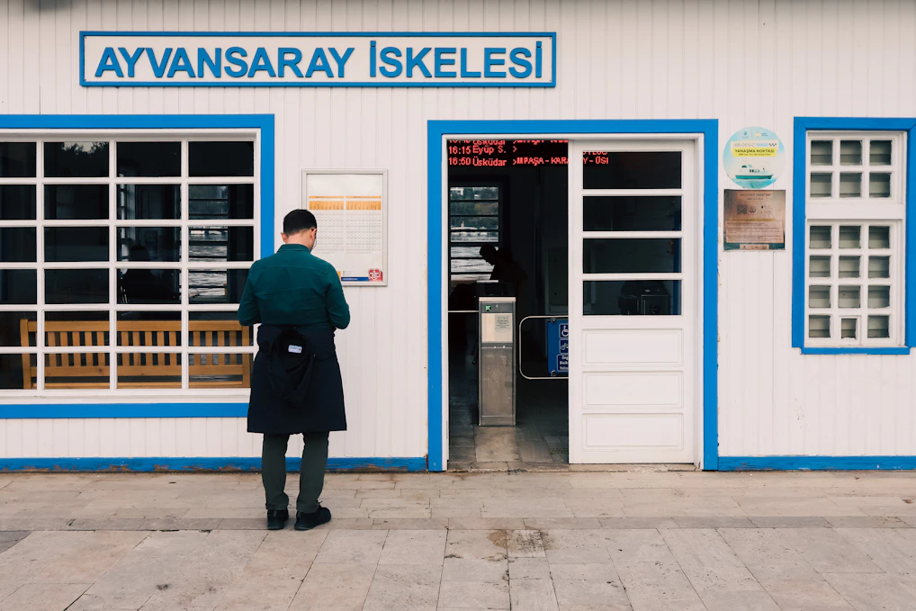 Man standing outside a ferry terminal building entrance.