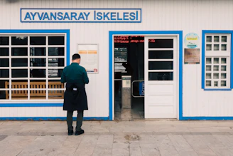 Man standing outside a ferry terminal building entrance.