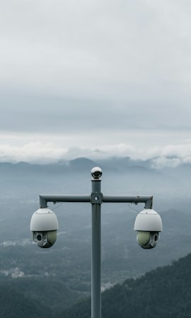 Two surveillance cameras on a pole with desert mountains in the background, a scene similar to roads across the Las Vegas valley