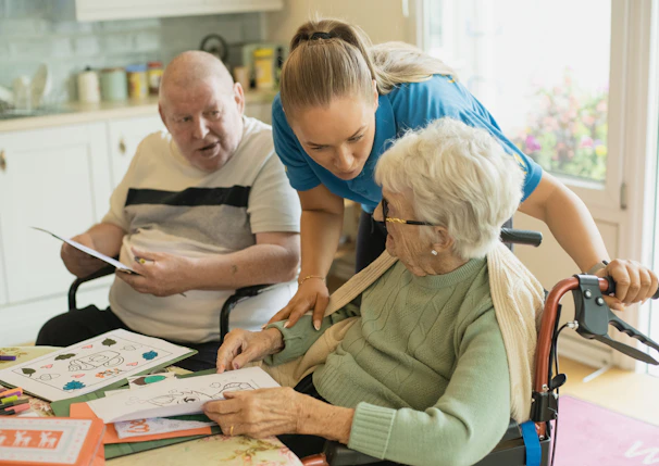 Caregiver assisting elderly couple with coloring