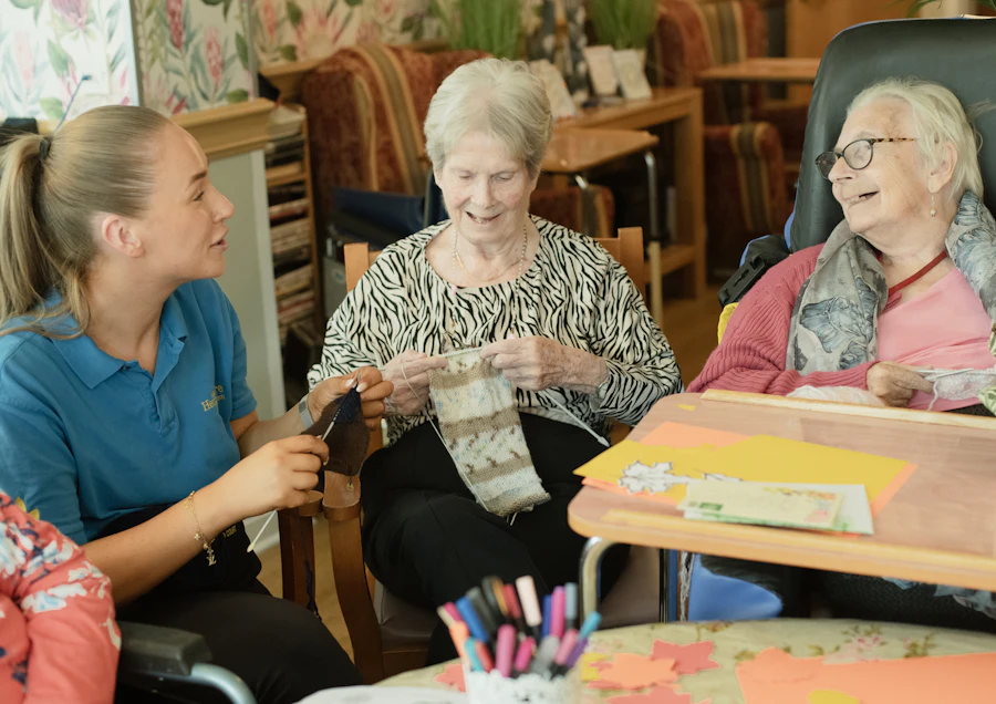 A caregiver helping two senior women with a calming knitting activity at home