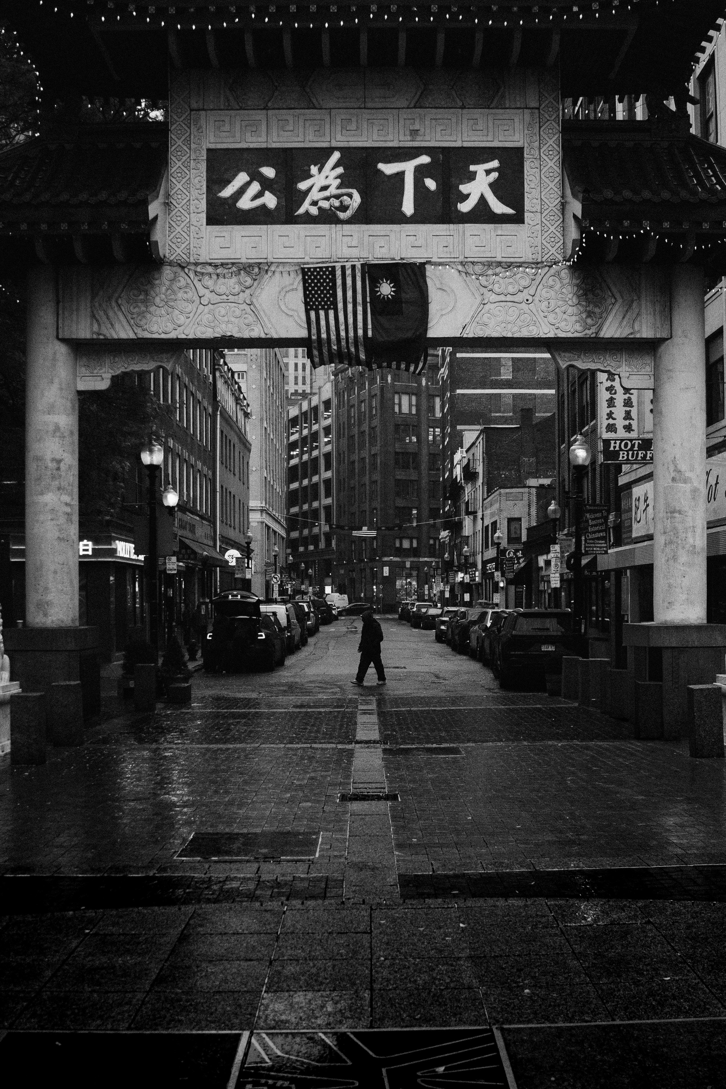 A lone figure walks through a chinatown gate at dusk.