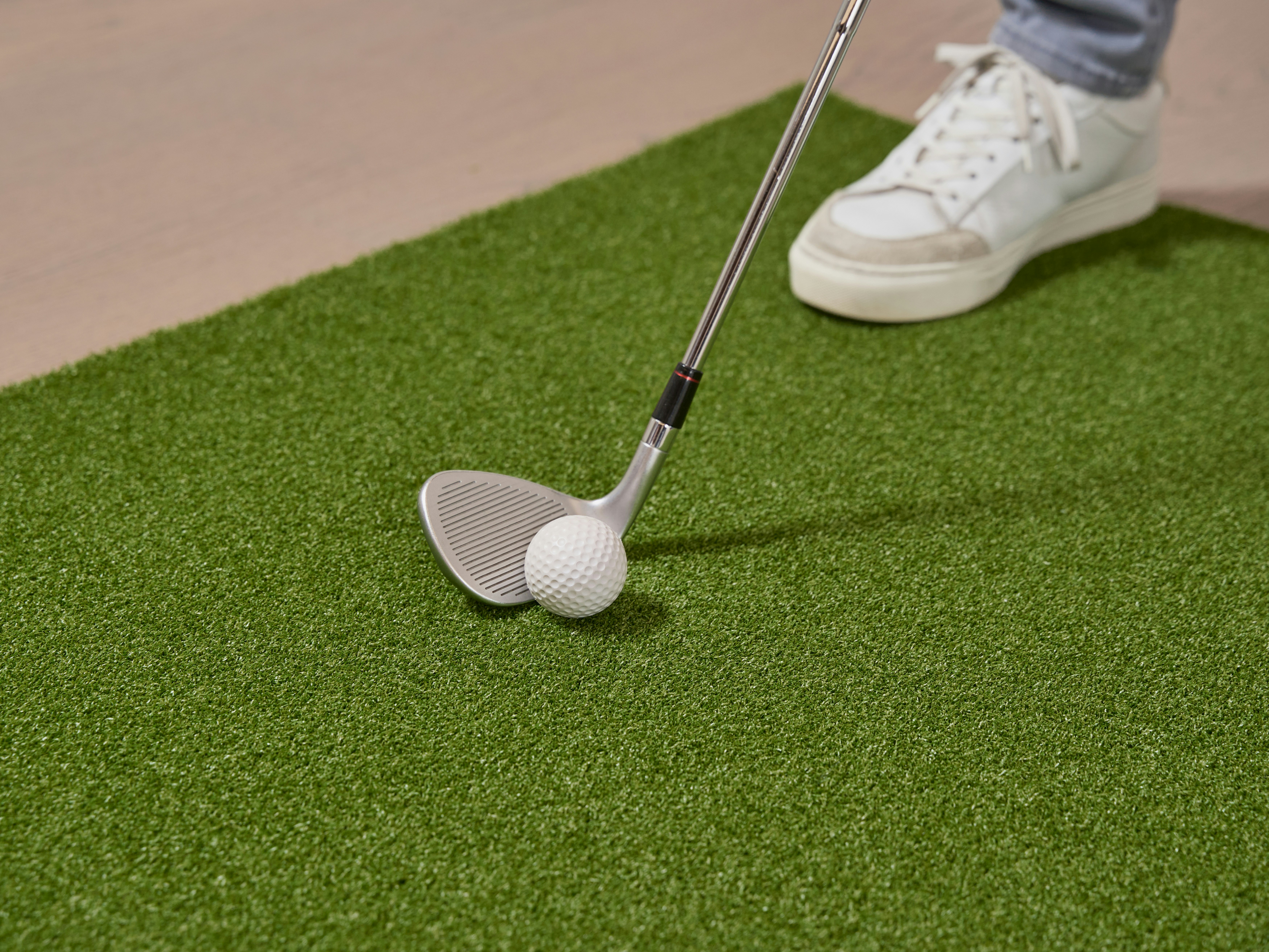 Person swinging golf club at ball on putting green