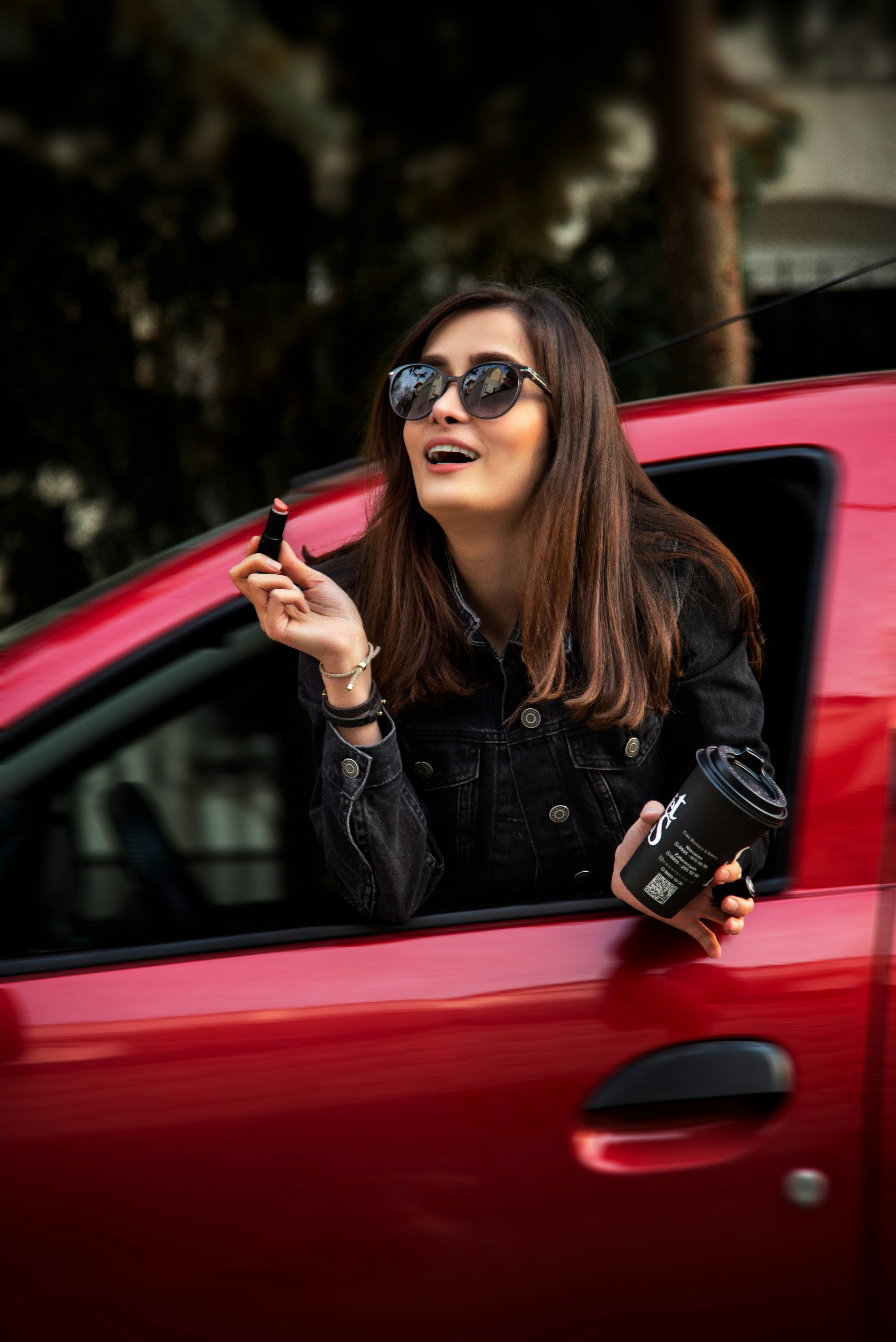 Woman applying lipstick in a red car