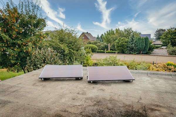 Two solar panels on a home roof with trees nearby