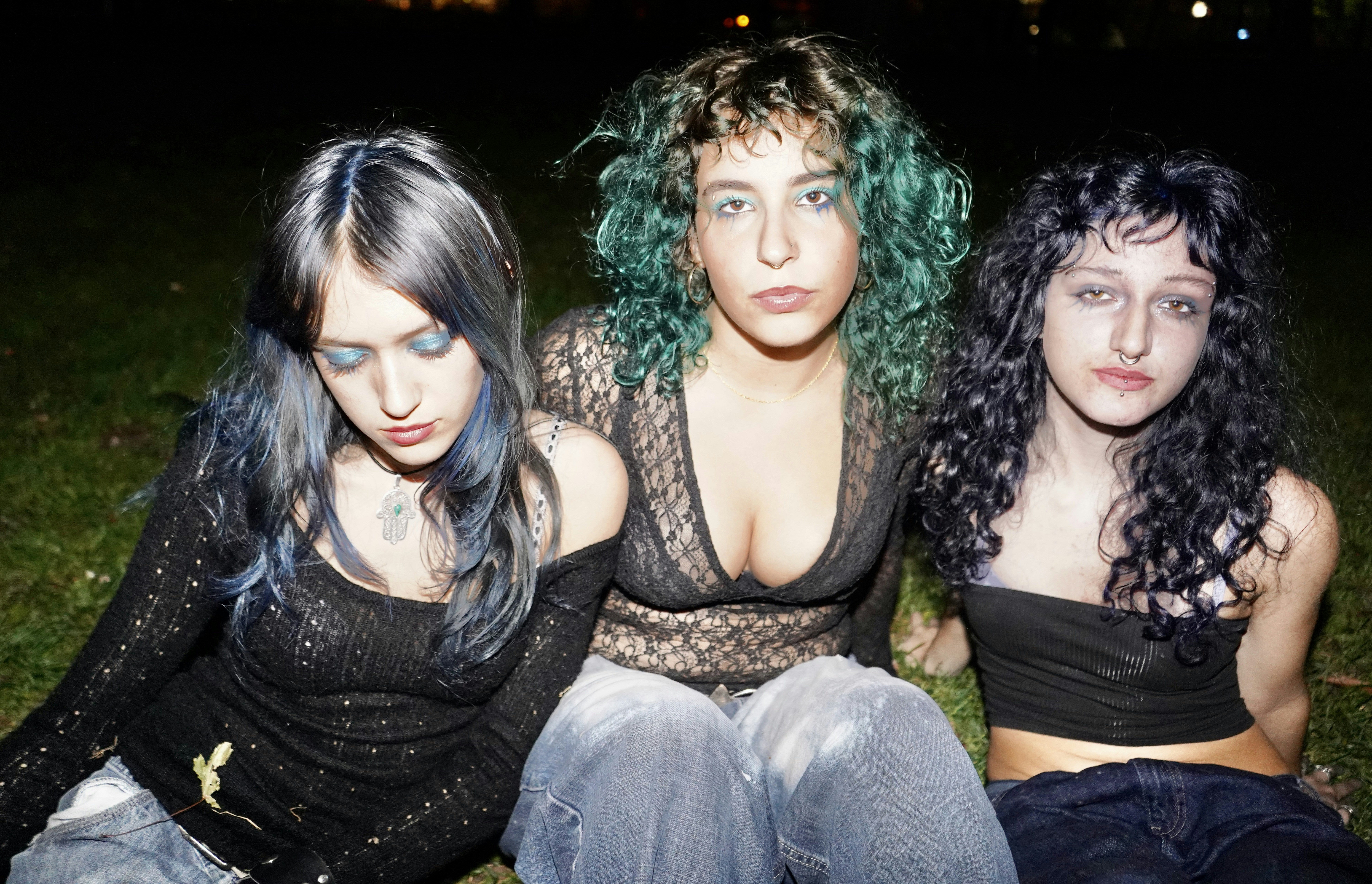Three young women with colorful hair posing outdoors