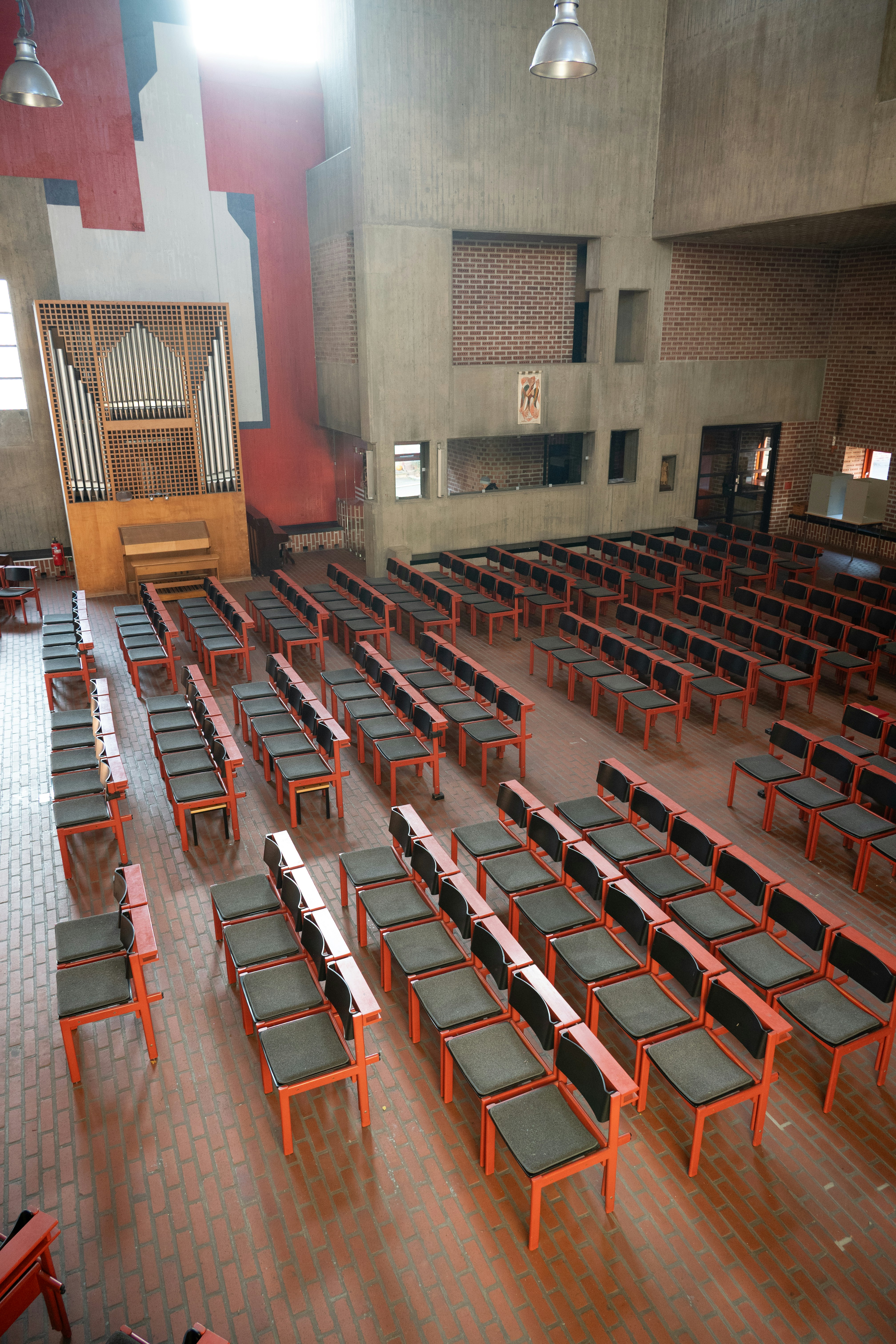 Rows of empty chairs in a large hall with organ.