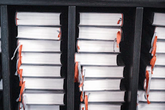 Stacks of white books with orange ribbons on shelves