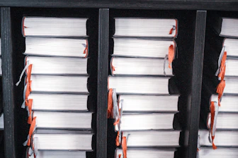 Stacks of white books with orange ribbons on shelves