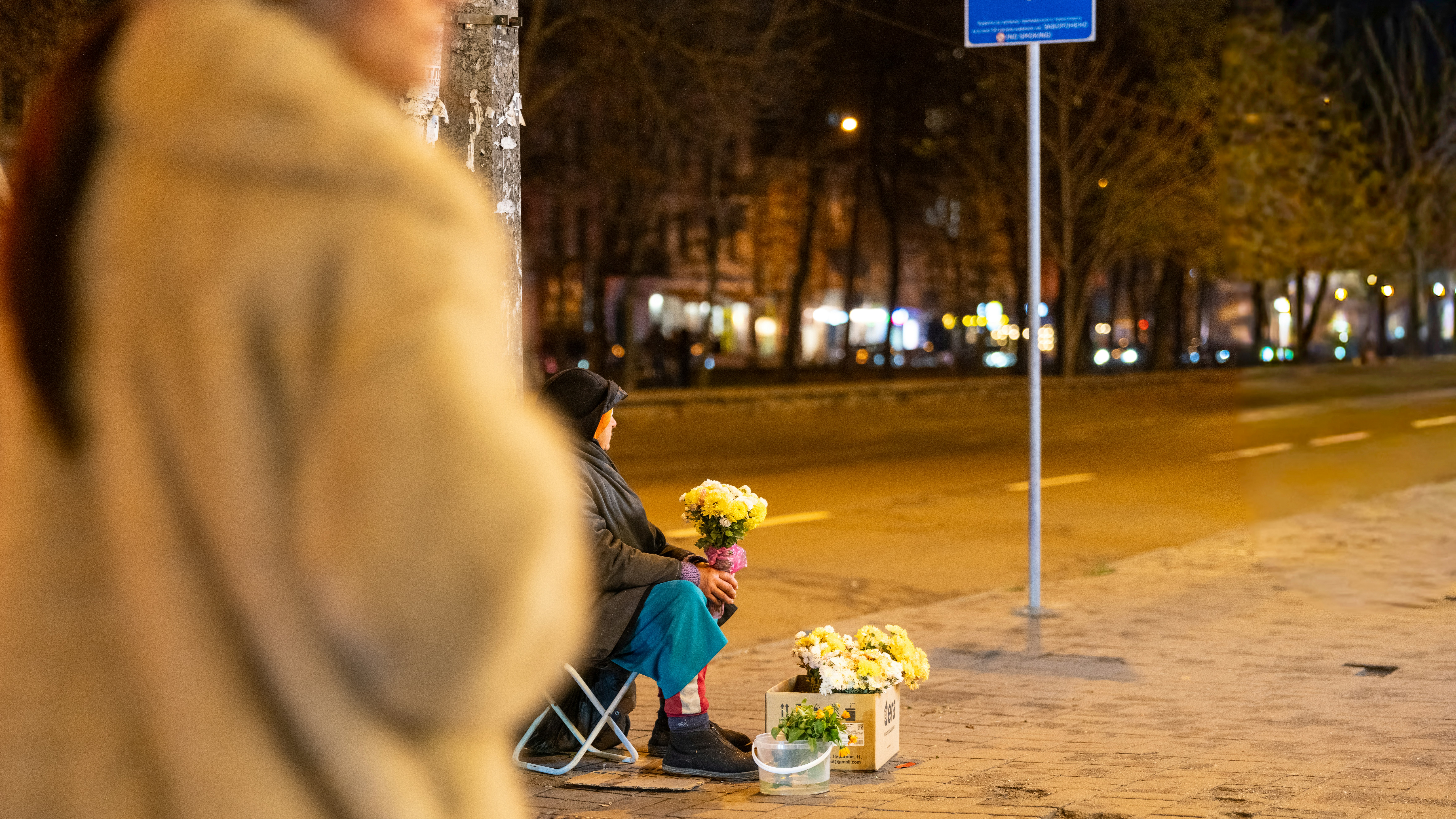 Woman selling flowers at night on sidewalk
