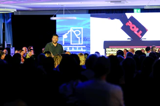 Man speaking on stage with audience watching