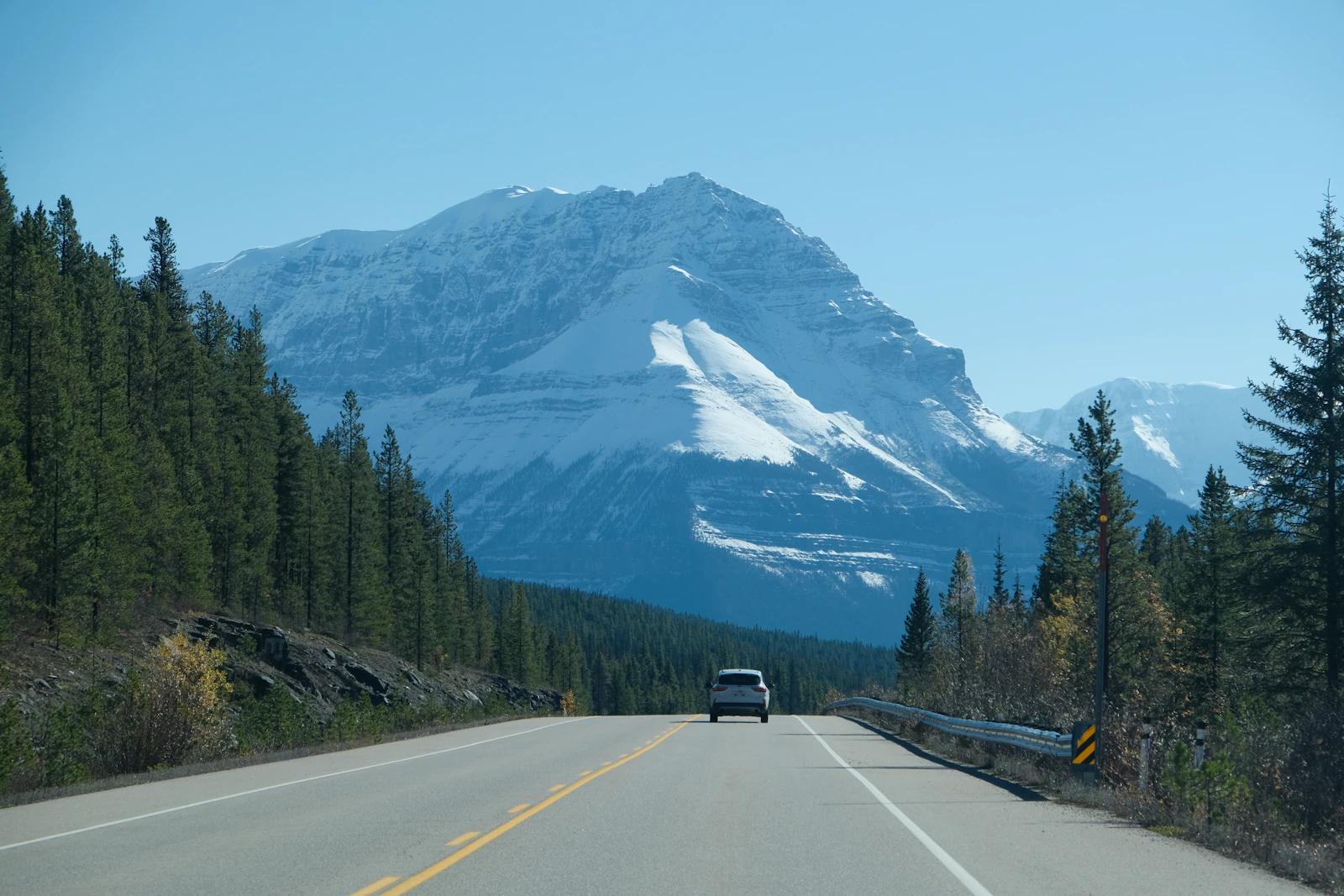 A car travels toward snowy mountains in Banff