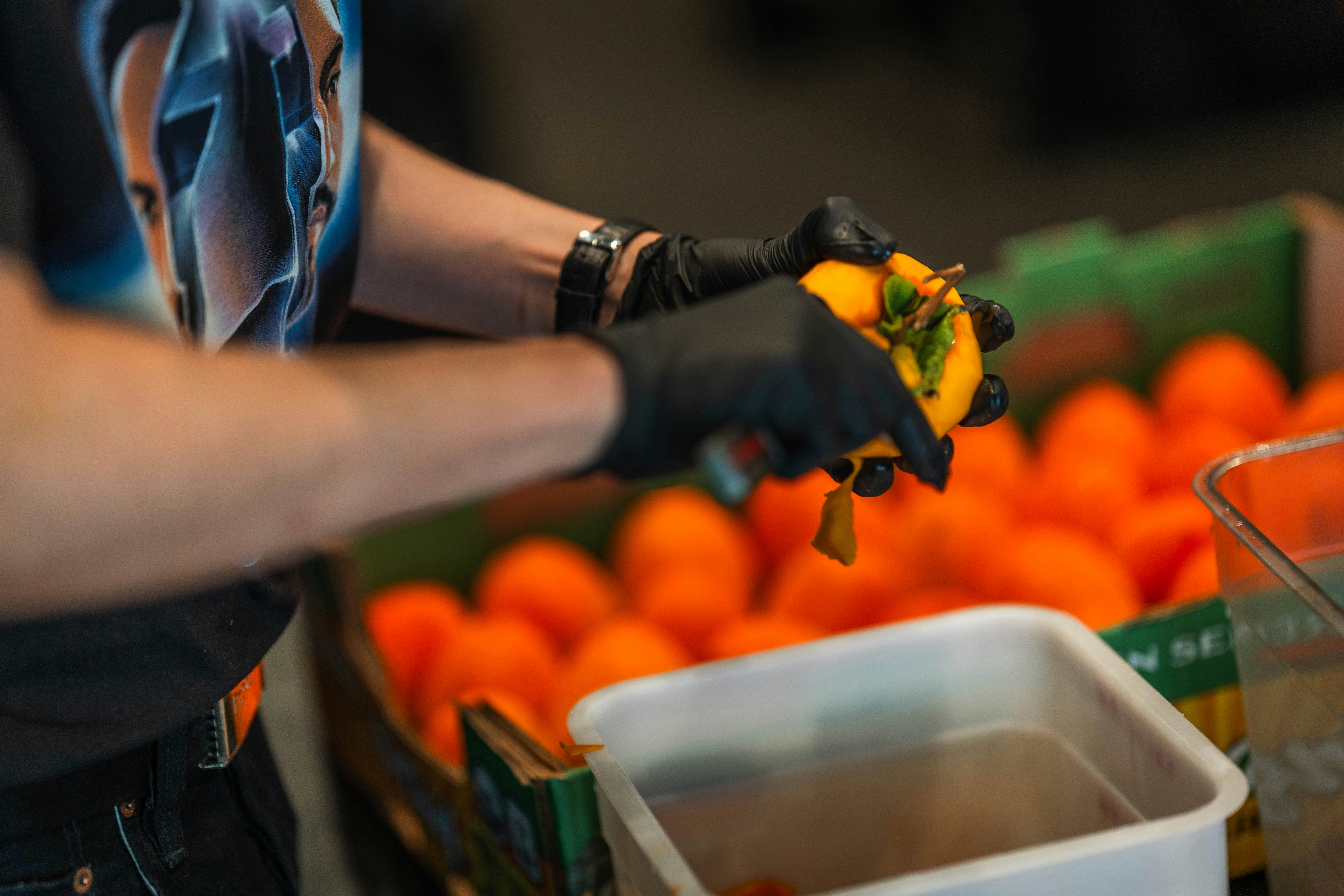 Person in black gloves preparing yellow bell peppers.