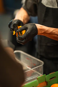 Chef wearing black gloves peeling an orange