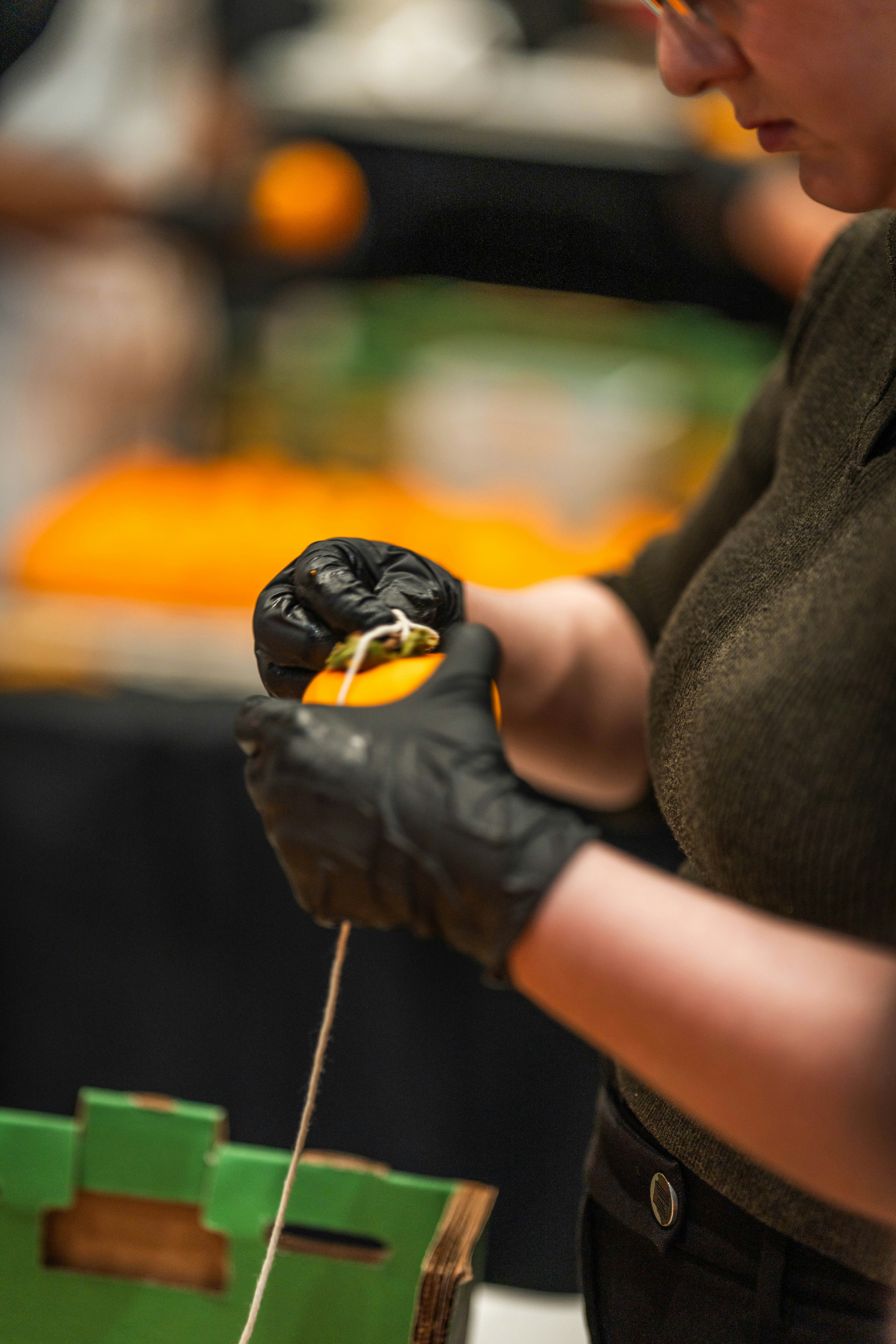 Person in black gloves preparing orange fruit