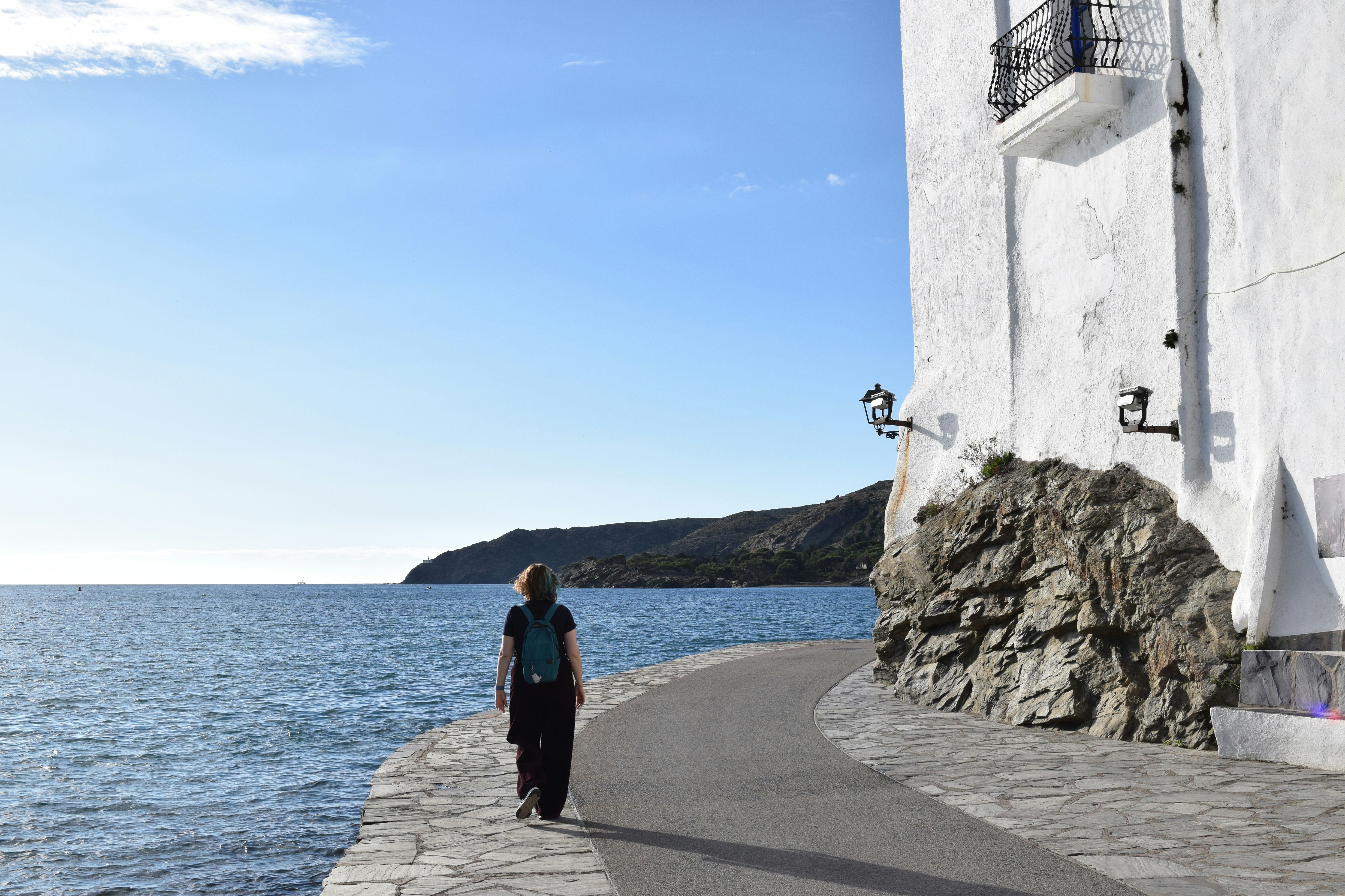 Woman walking along a coastal path beside the sea.