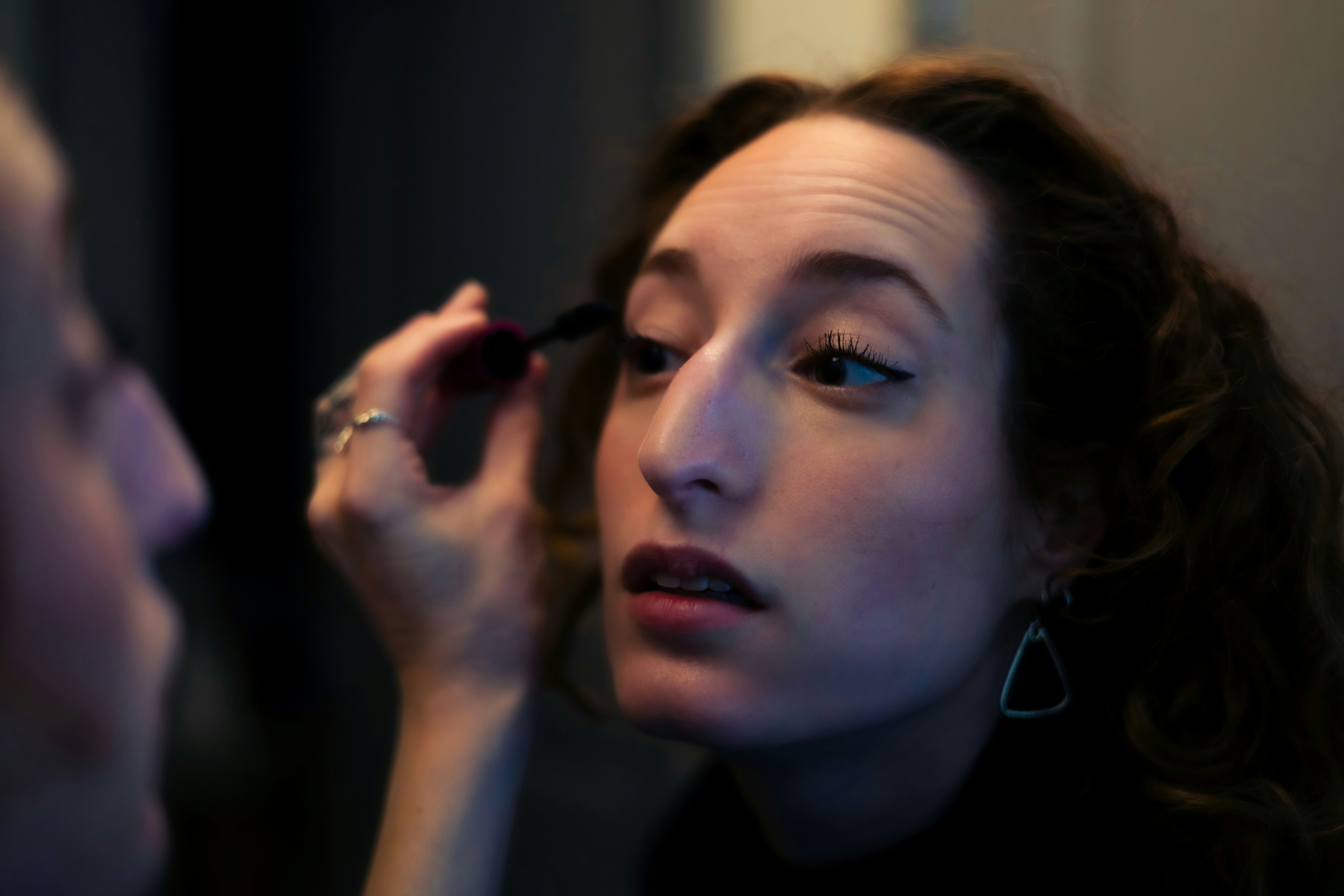 Woman applying mascara in the mirror
