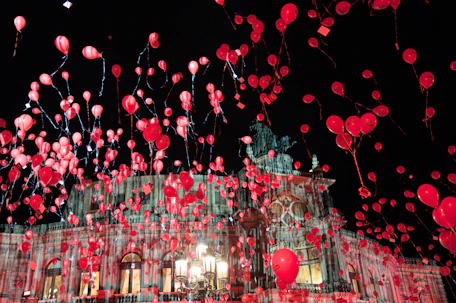 Many red balloons float up into the night sky.