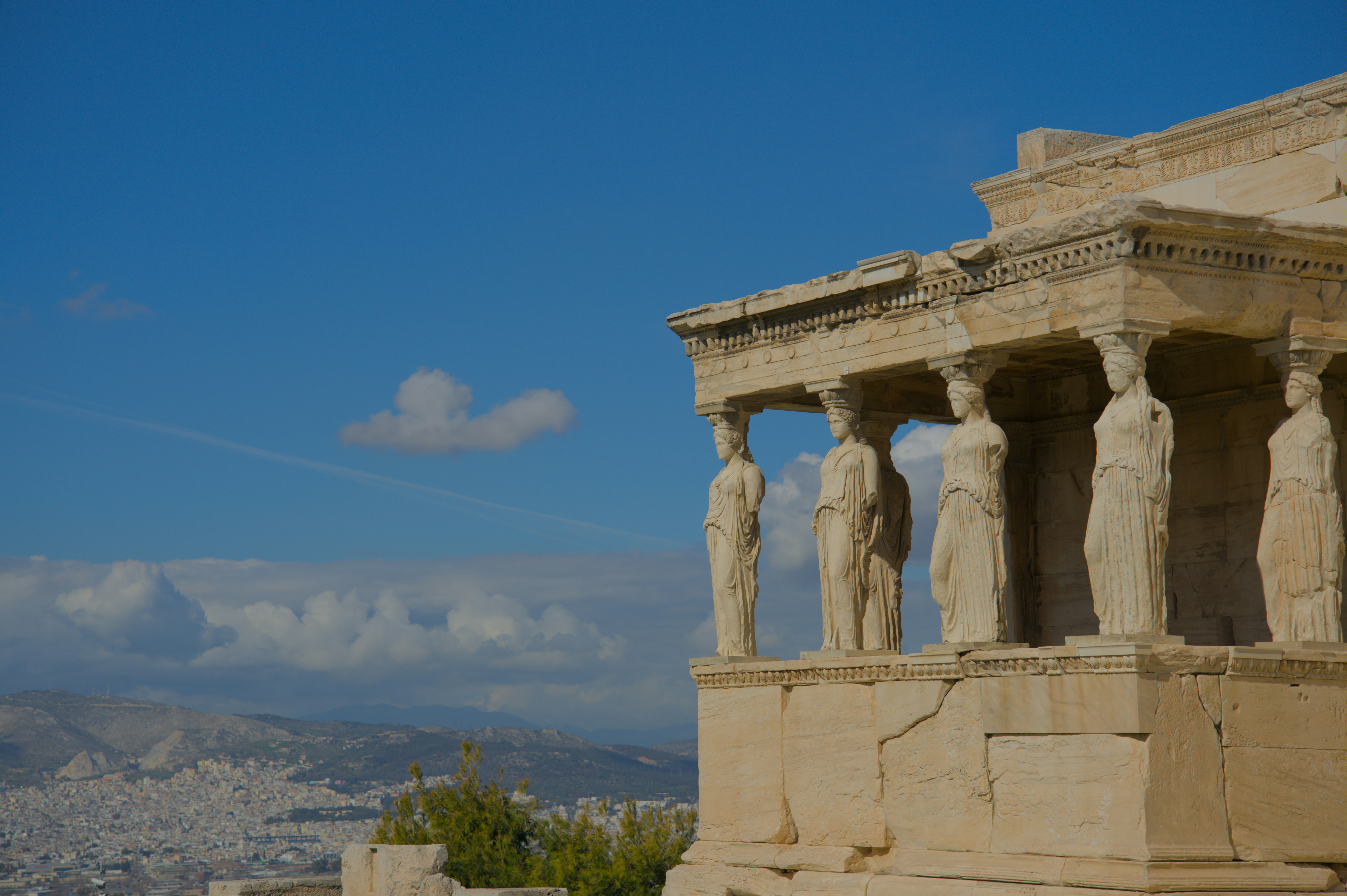 Ancient greek temple ruins with statues under blue sky
