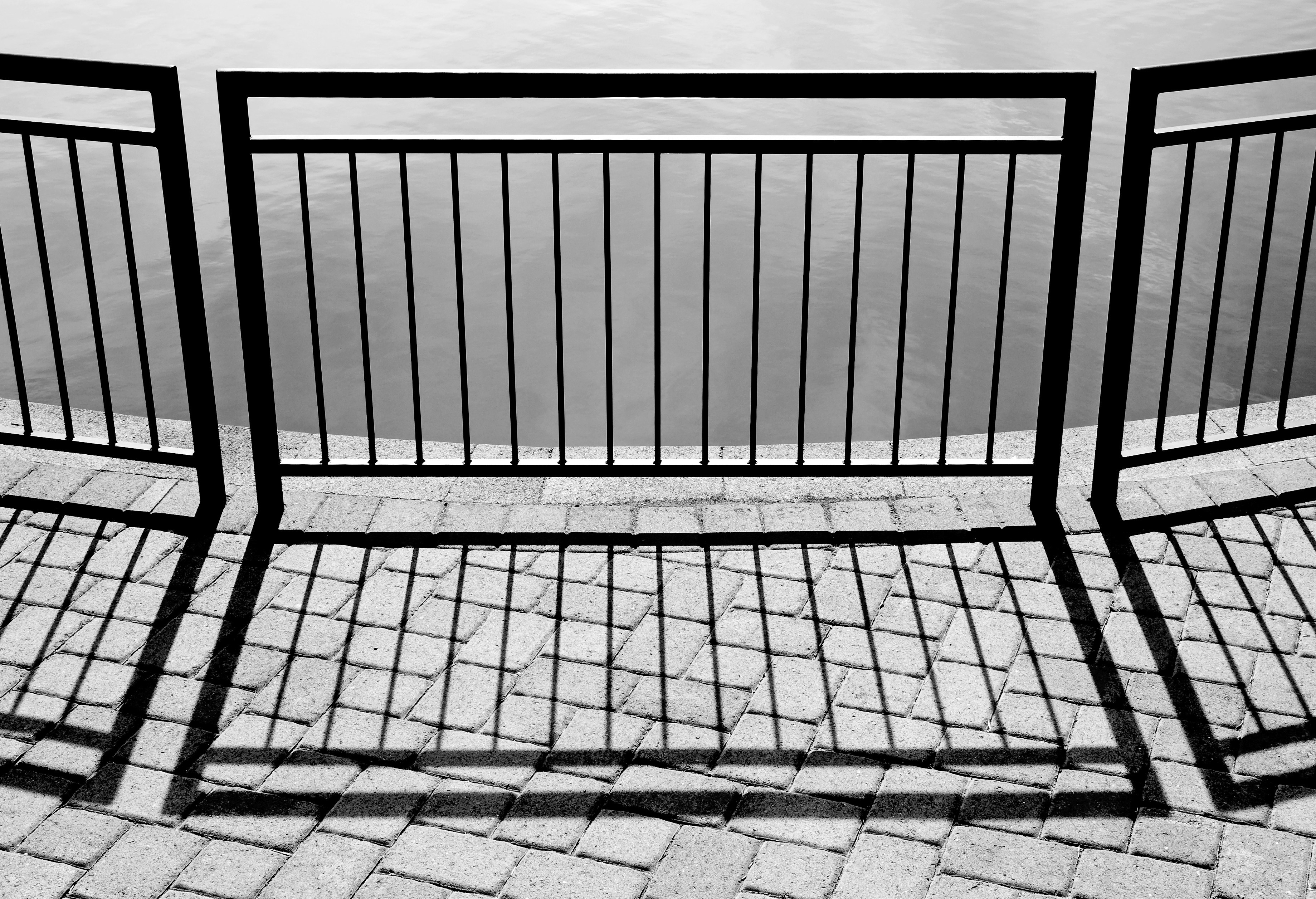 Black metal railing casts shadows on paved ground