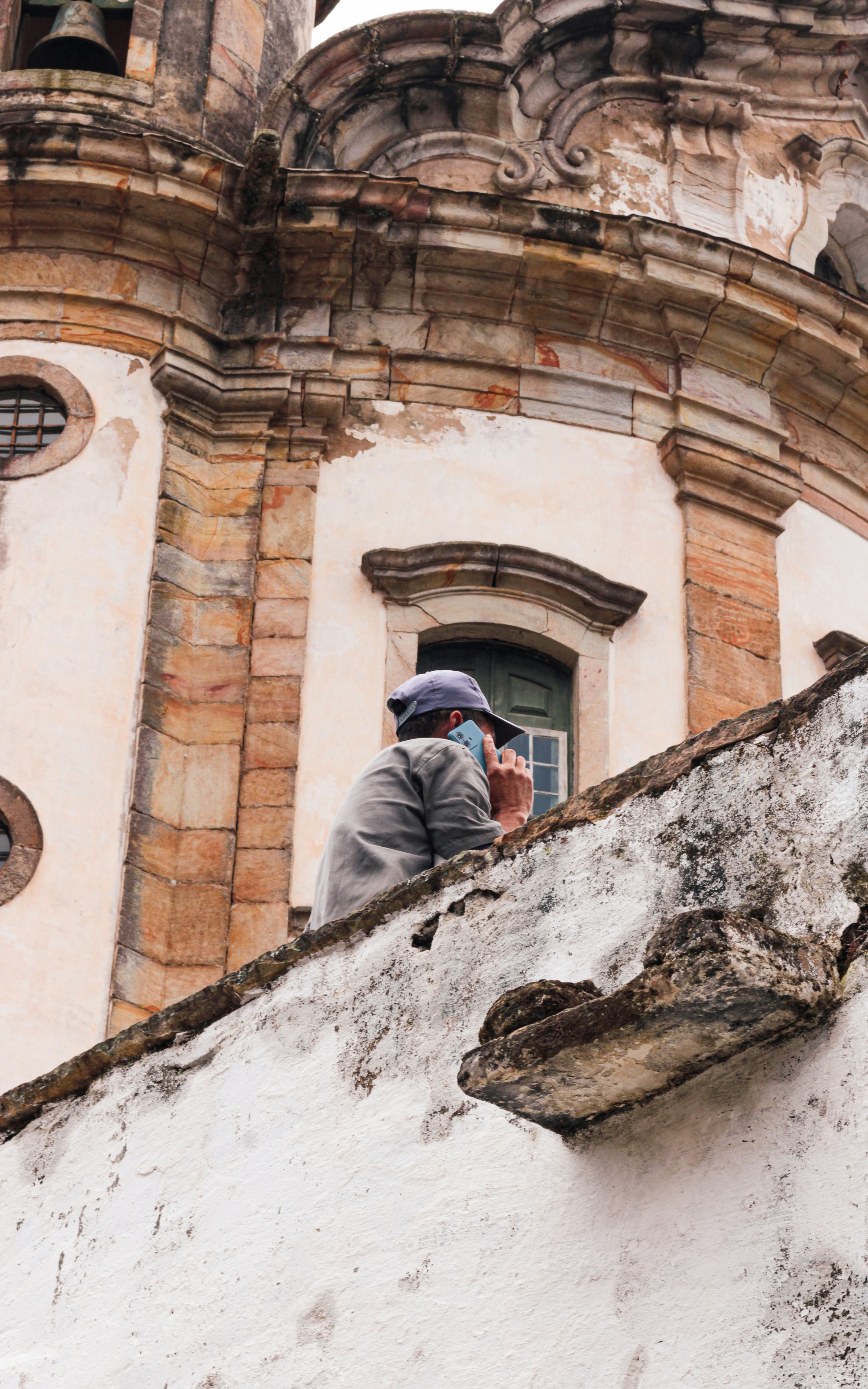 Person wearing a hat and mask looks at building.
