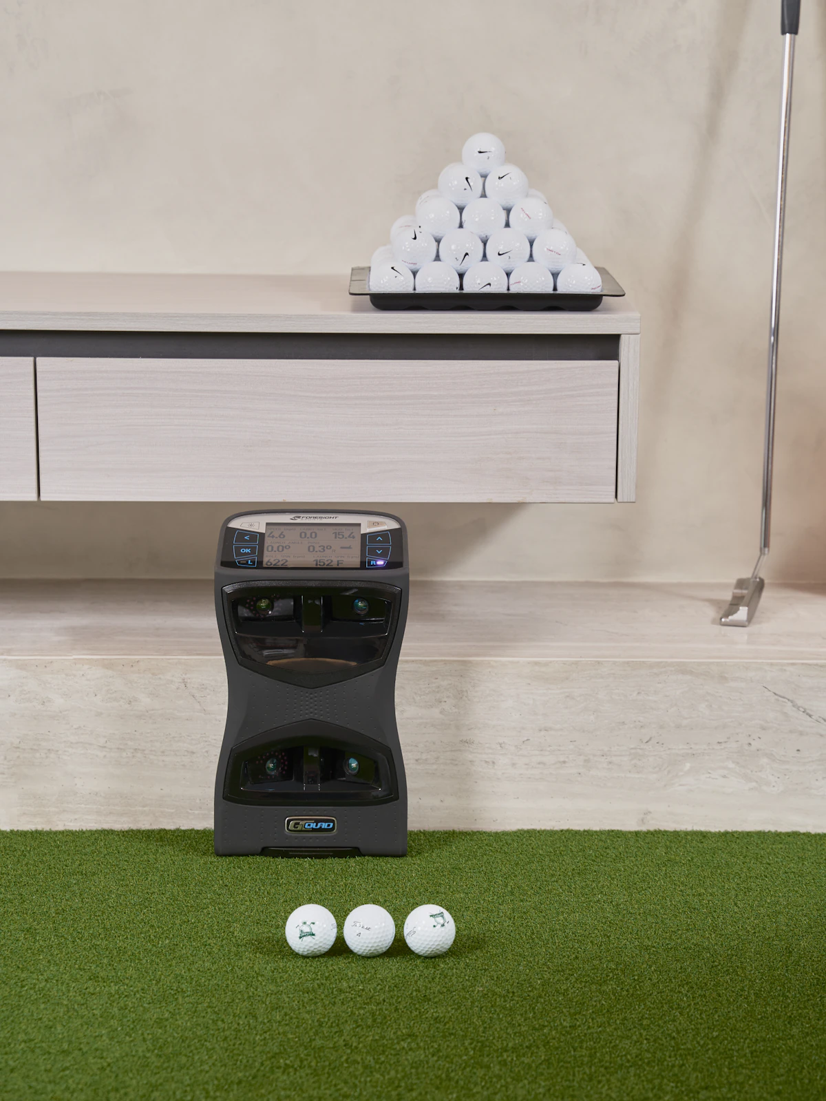 Golf launch monitor sitting on a hitting mat pointed at a golf ball