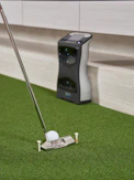 Golf club and ball on artificial turf with device.